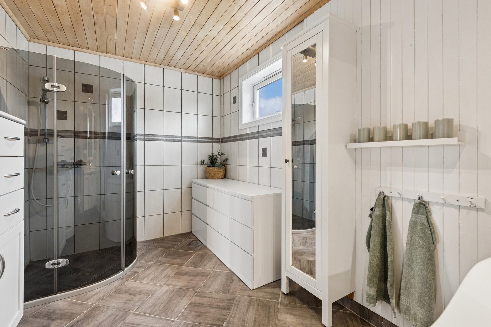 Badet har flislagt gulv og dusjhjørne. Galleribilde