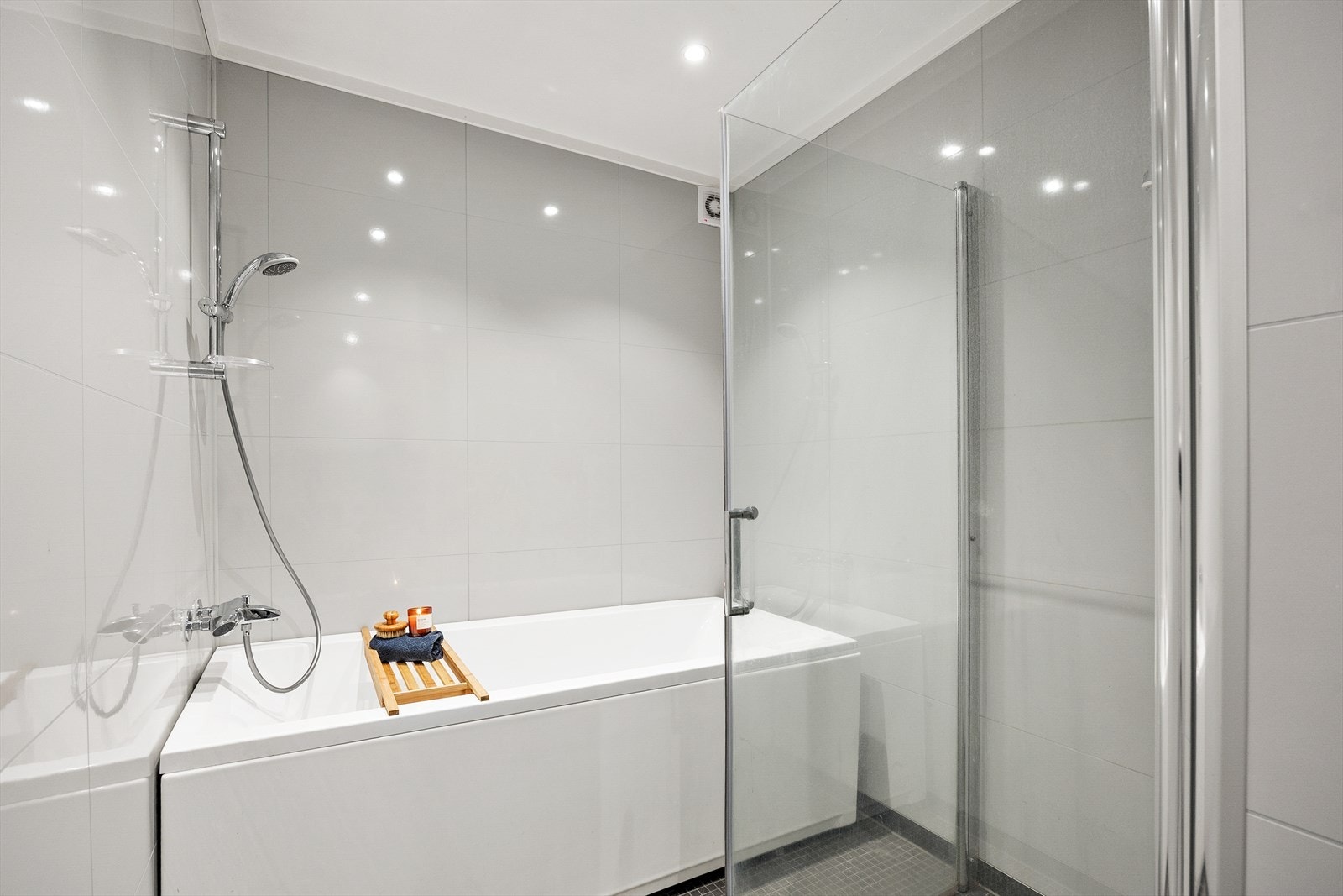 Badet er innredet med badekar, dusjhjørne, vegghengt toalett og servant i servantskap. Galleribilde