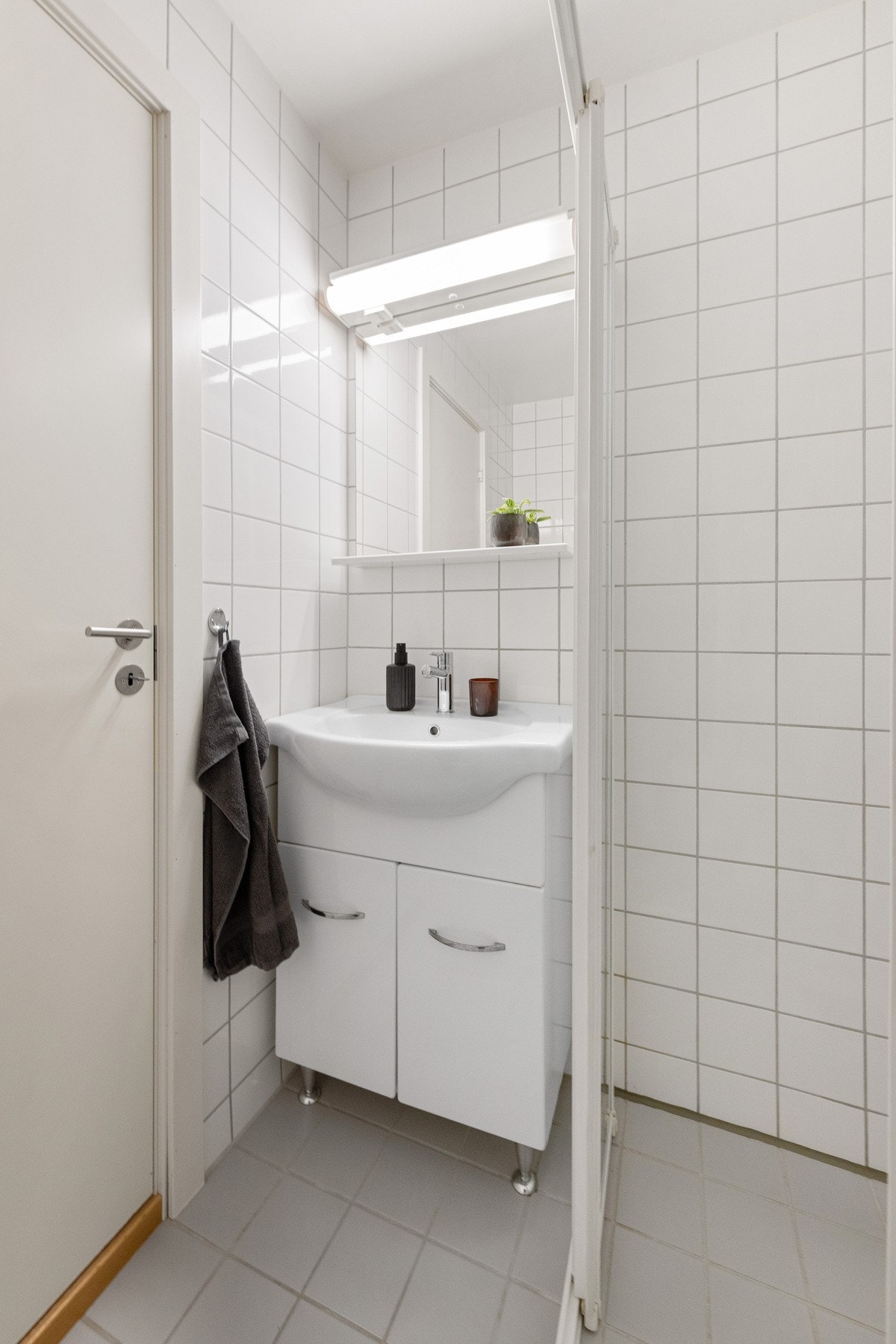 Flislagt bad med grå gulvfliser og hvite fliser på veggene. Galleribilde