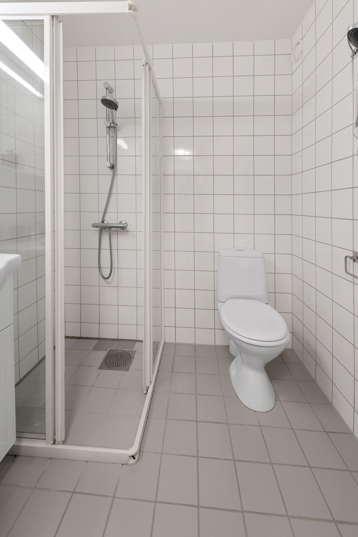 Badet er innredet med servantinnredning med nedfelt servant, frittstående toalett og dusjhjørne med glassdører. Galleribilde