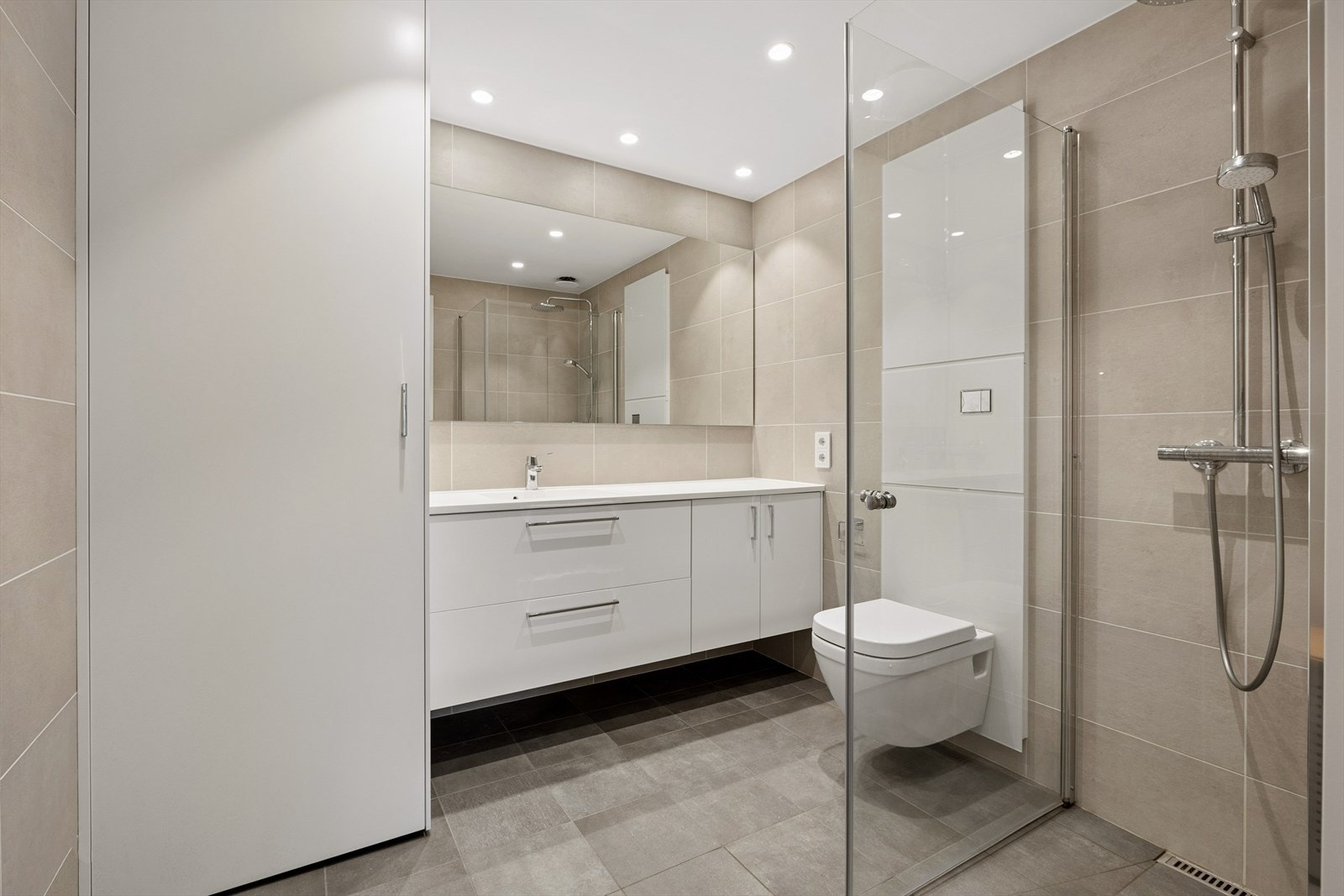 Badet fremstår moderne og delikat med oppgraderte Ragno Studio-fliser, regndusj, vegghengt toalett, downlights og skjult opplegg for vaskemaskin. Galleribilde