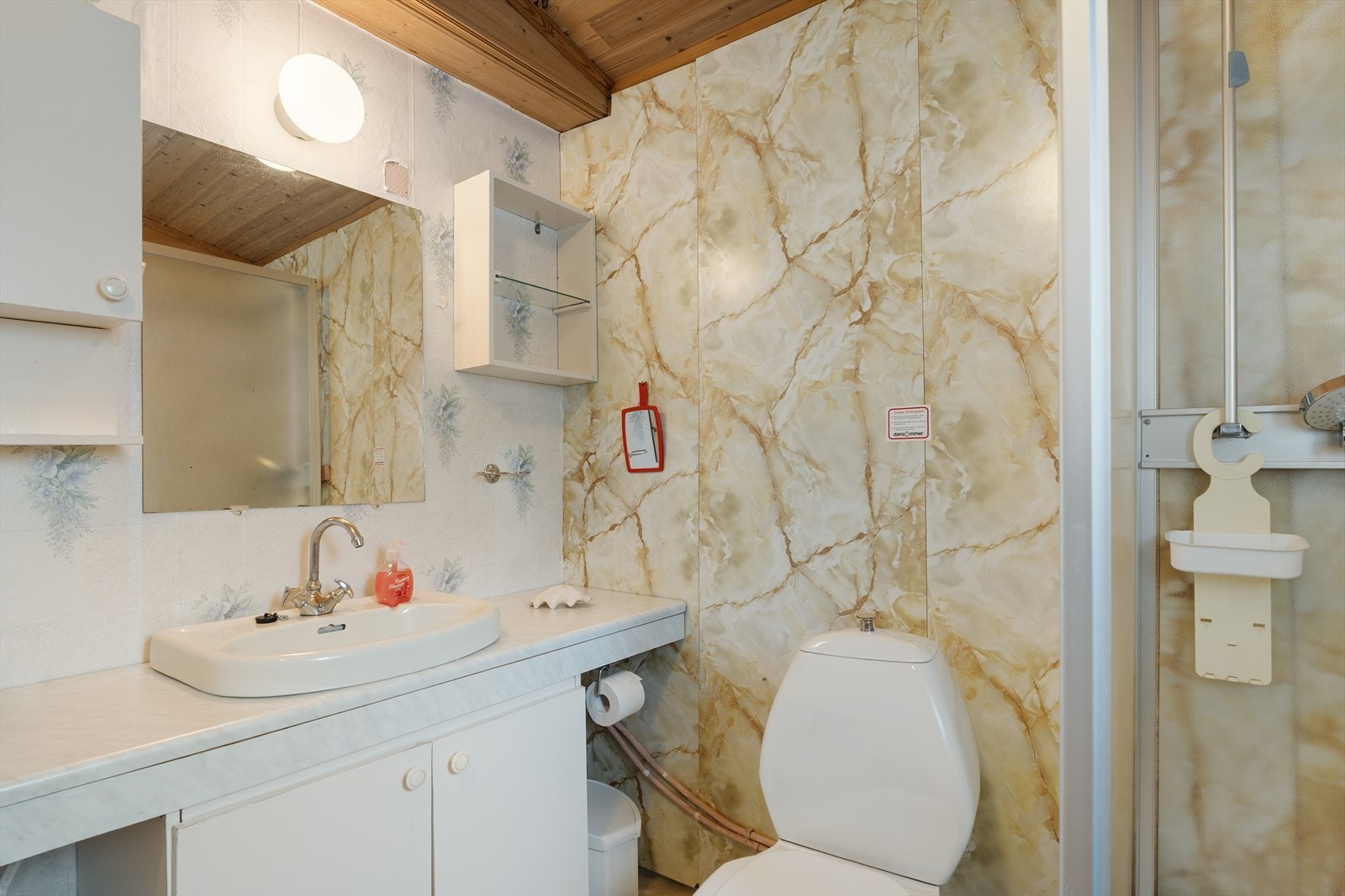Bad med belegg på gulv og plater/tapet på vegg. Det er videre på badet varmeovn, toalett, dusjkabinett, baderomsinnredning med vask, 3 overskap og speil på
vegg. Galleribilde