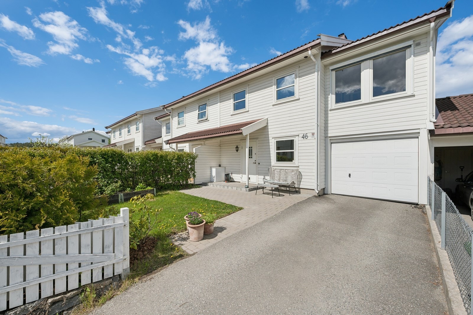 Uteområdet fremstår ryddig og velstelt, med en relativt flat tomt beplantet med plen og hekk. Asfaltert innkjørsel til garasje, samt brostein og støttemur, gir et helhetlig og pent uttrykk. Galleribilde