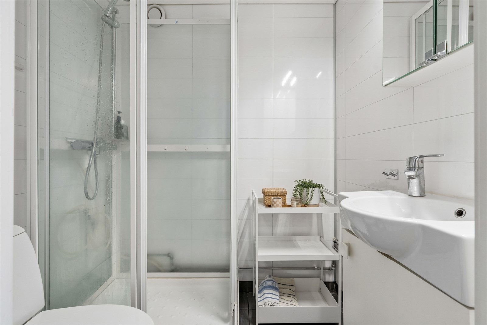 Badet inneholder toalett, dusjkabinett og servant med skapinnredning. Galleribilde