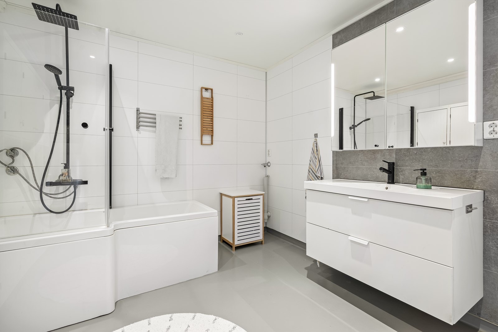 Badet er innredet med servantinnredning, speilskap med lys, vegghengt toalett og badekar med dusjvegg. Opplegg for vaskemaskin også her. Galleribilde
