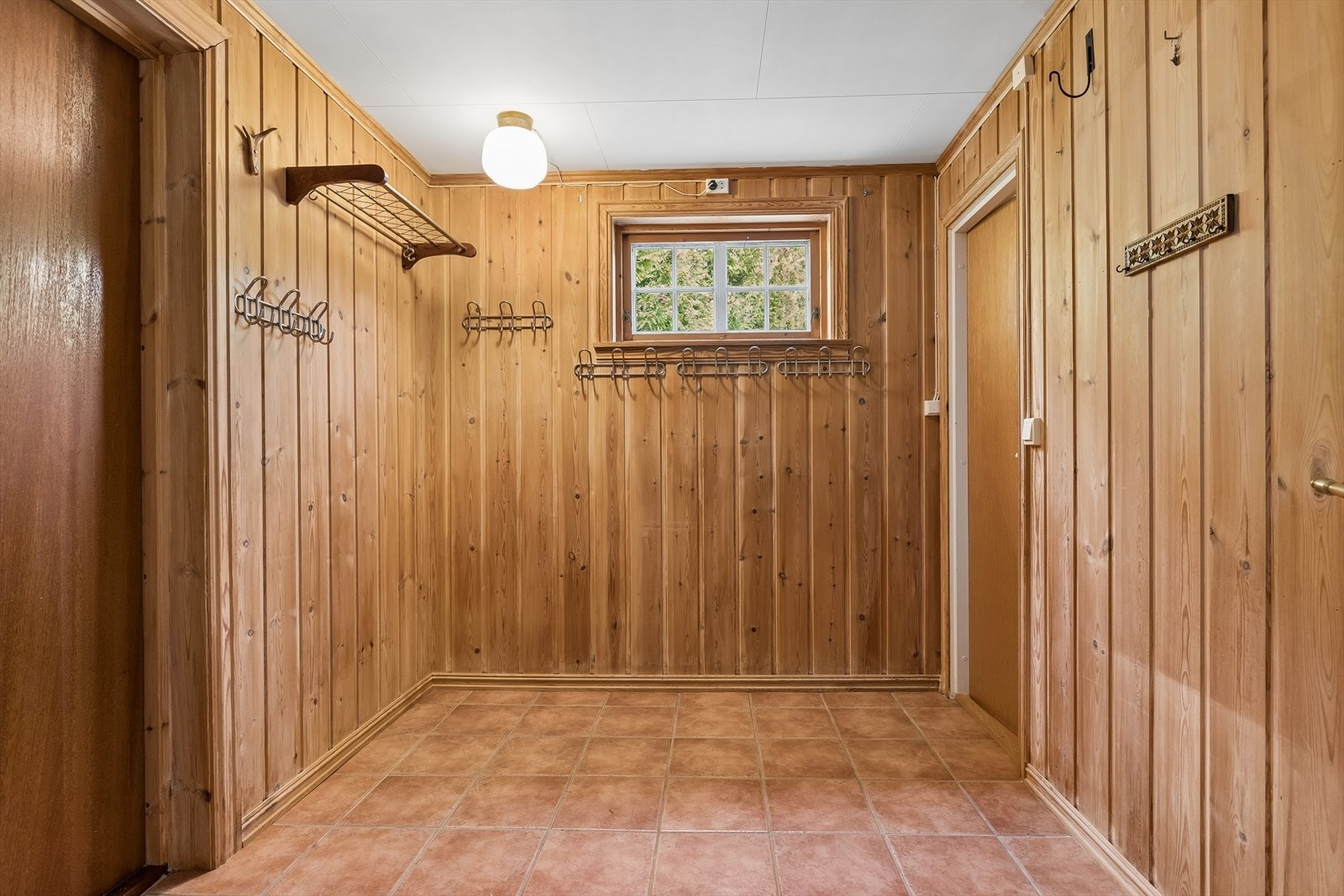 Romslig entré med god plass til yttertøy og sko. Veggene er kledd med trepanel. Galleribilde