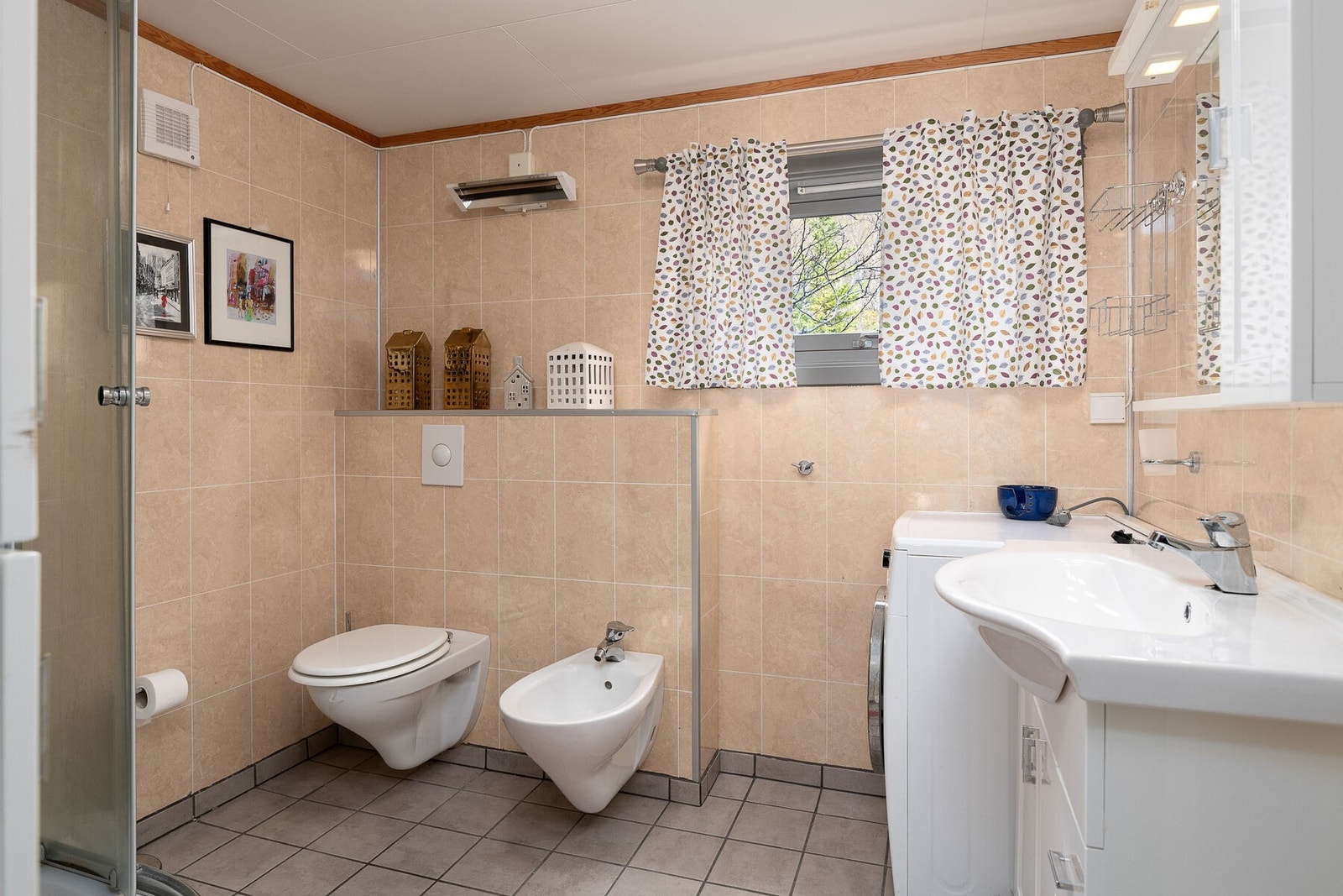 Badet har flislagt gulv med elektriske varmekabler, vegghengt toalett og bidet. Galleribilde
