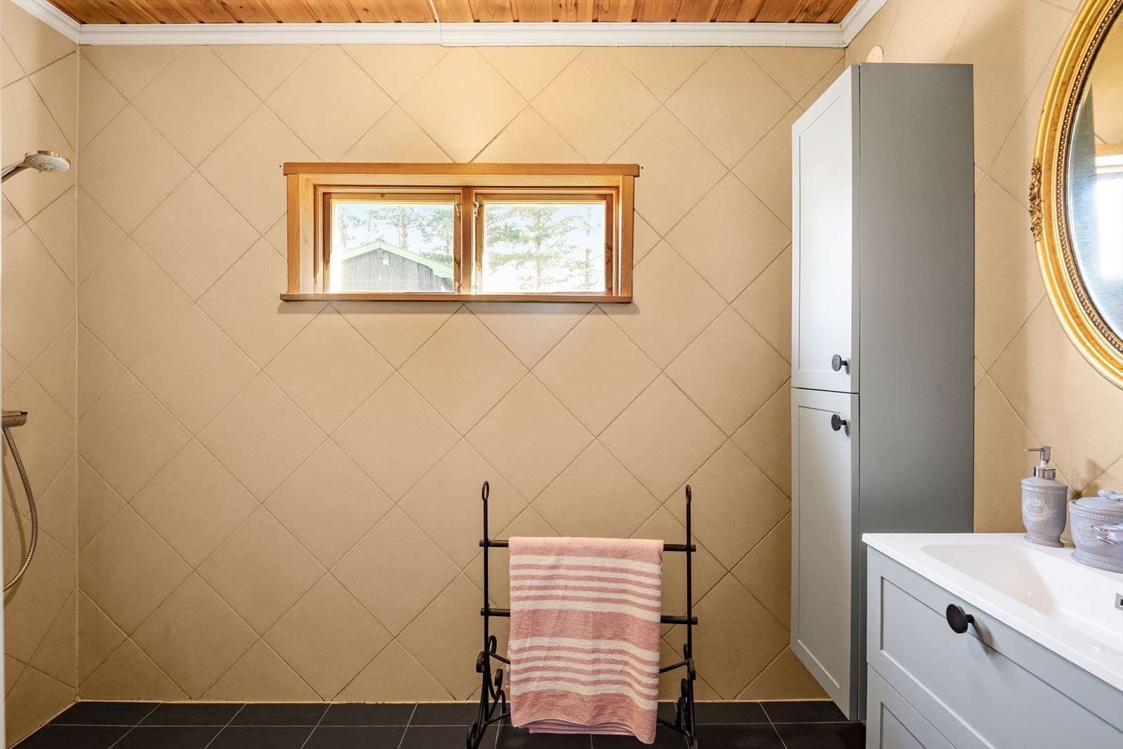 Badet er innredet med servantinnredning og høyskap, toalett og veggmontert dusjbatteri. Galleribilde