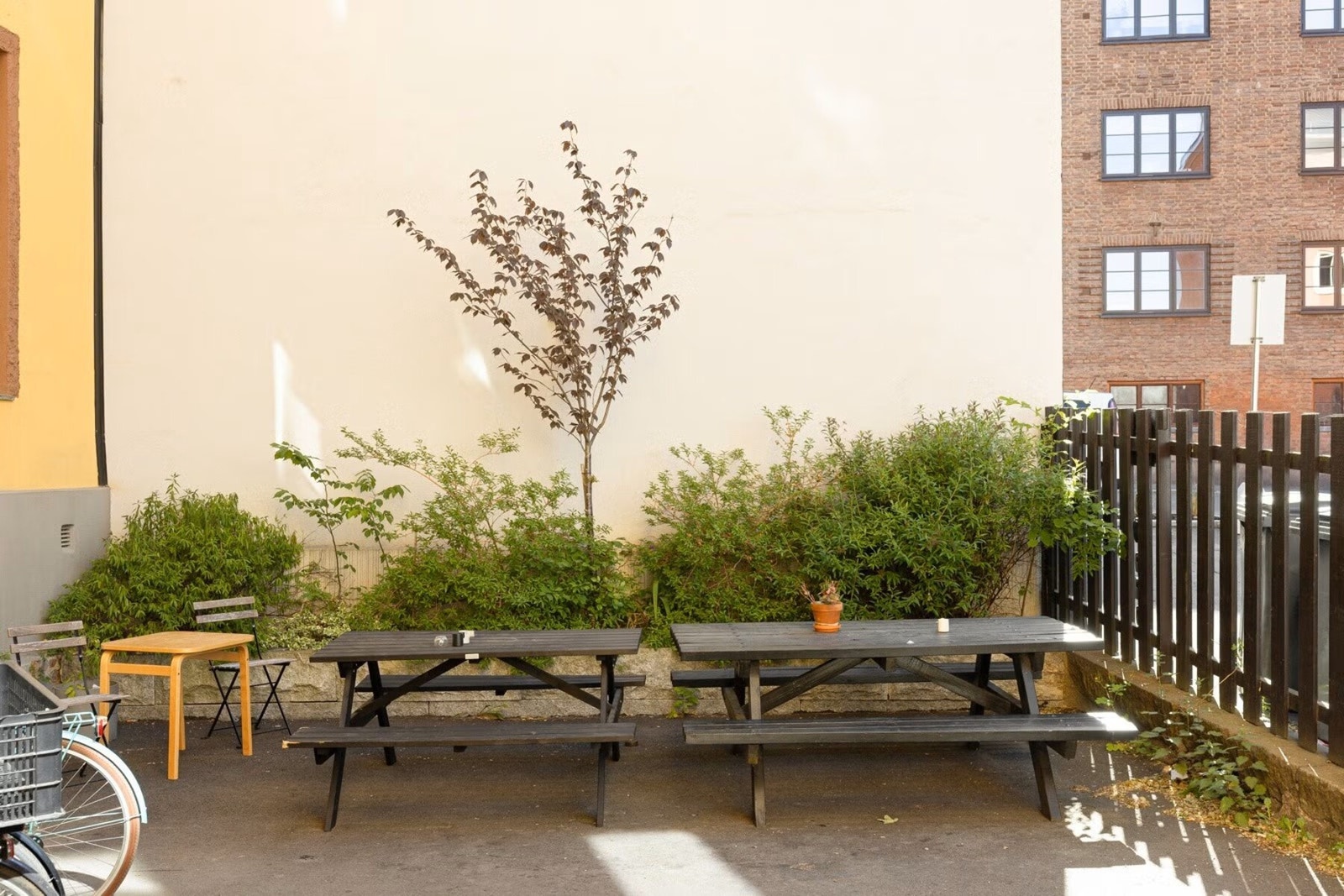 Sameiet har stensatt felles gårdsrom med sittegruppe, avgrenset med gjerde mot gate. Flott sommerbakgård med sittegrupper Galleribilde