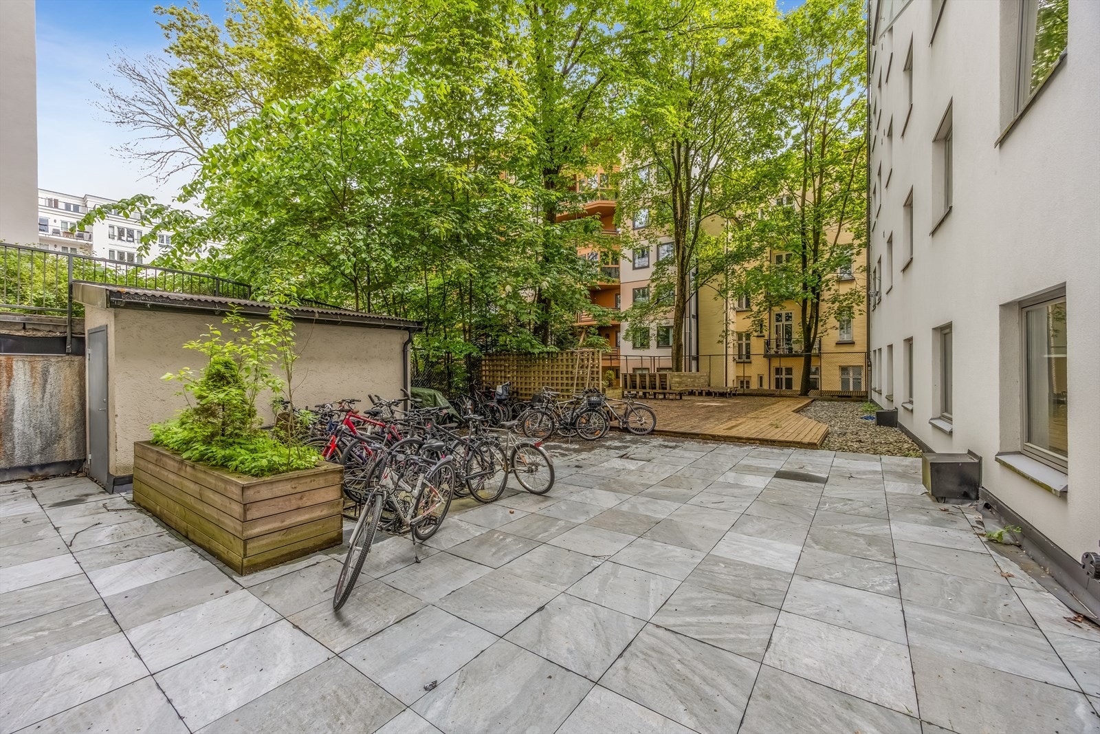 Pent opparbeidet bakgård med sittegrupper, beplantning og sykkelparkering. Galleribilde