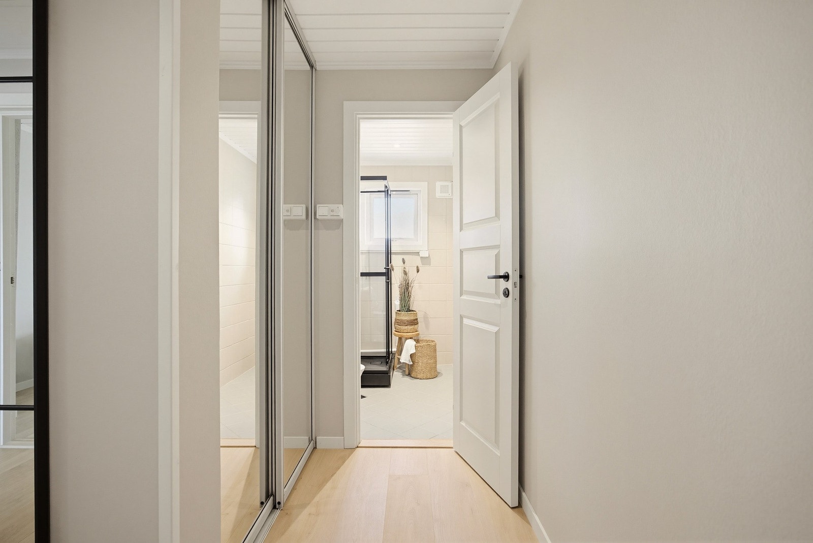 Langs den ene veggen finner du en skyvedørsgarderobe med speilfronter som både gir rikelig med oppbevaringsplass til yttertøyet og bidrar til å forsterke romfølelsen. Galleribilde