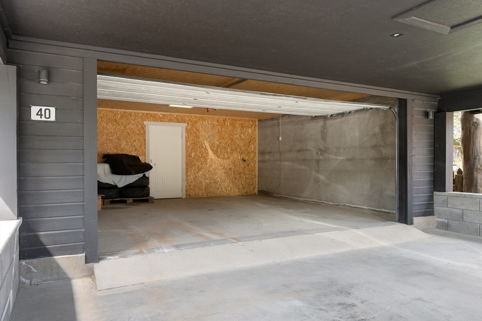 Garasjen har støpt gulv og leddport av metall med portåpner. Galleribilde