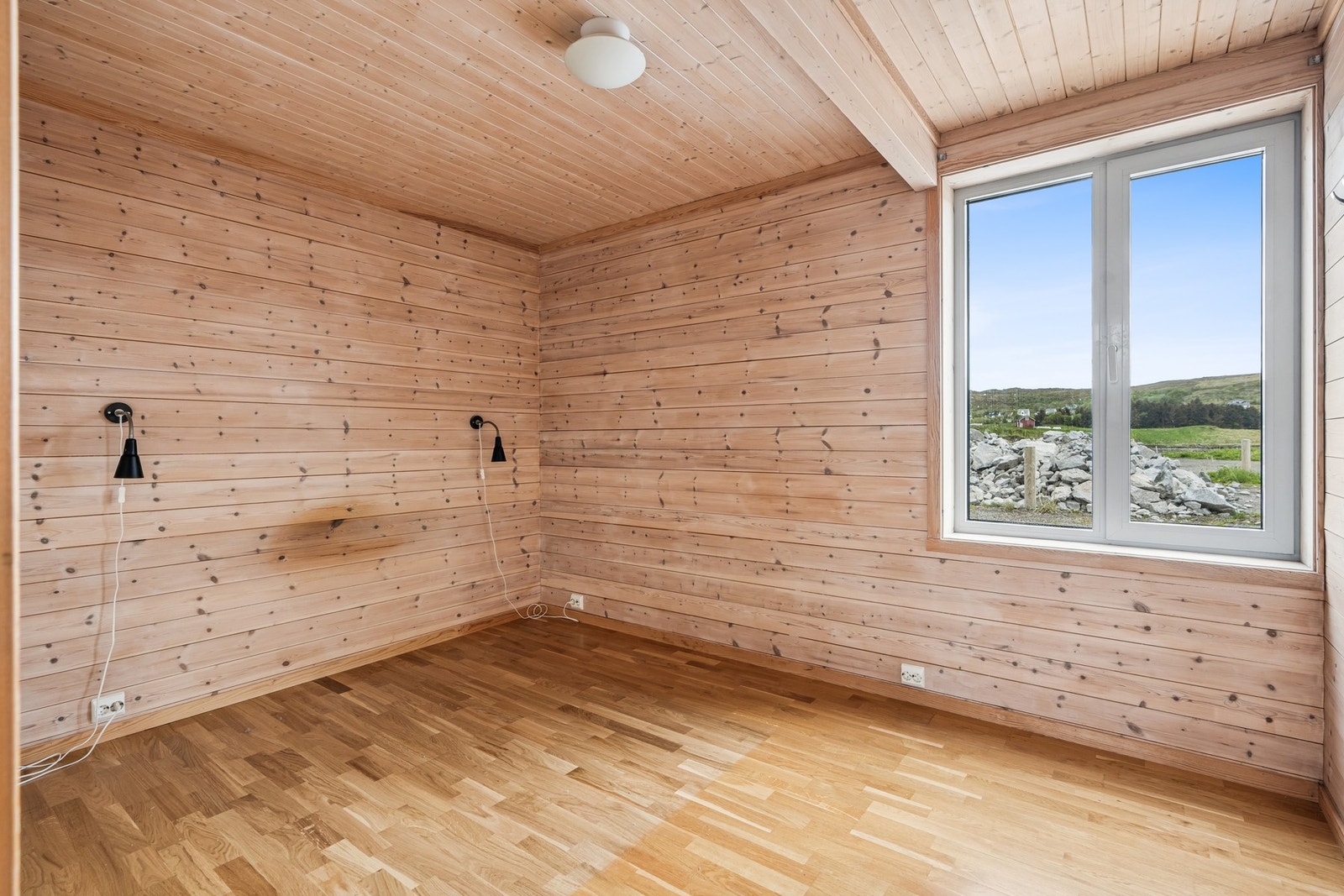 Soverom i hovedetasjen med parkett på gulvet og vegger kledd i trepanel. Galleribilde