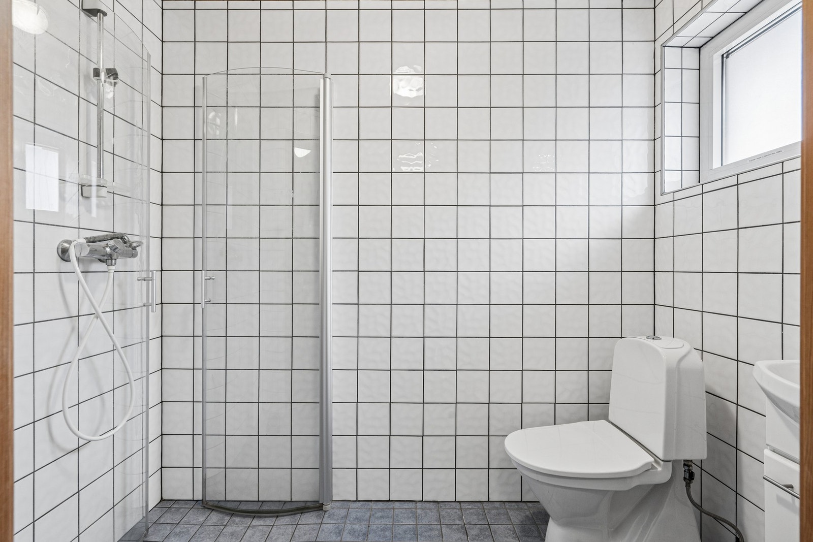 Flislagt bad med elektriske varmekabler i gulvet. Rommet er utstyrt med dusjhjørne, toalett og servant. Galleribilde