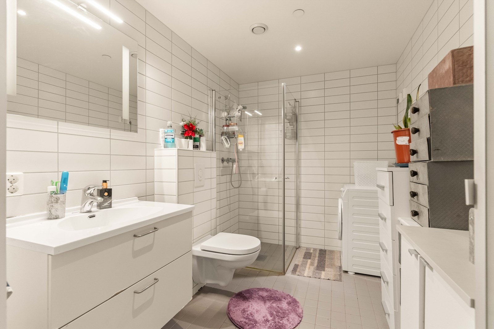Flislagt bad med vannbåren gulvvarme, vegghengt toalett, downlights og opplegg for vaskemaskin. Galleribilde