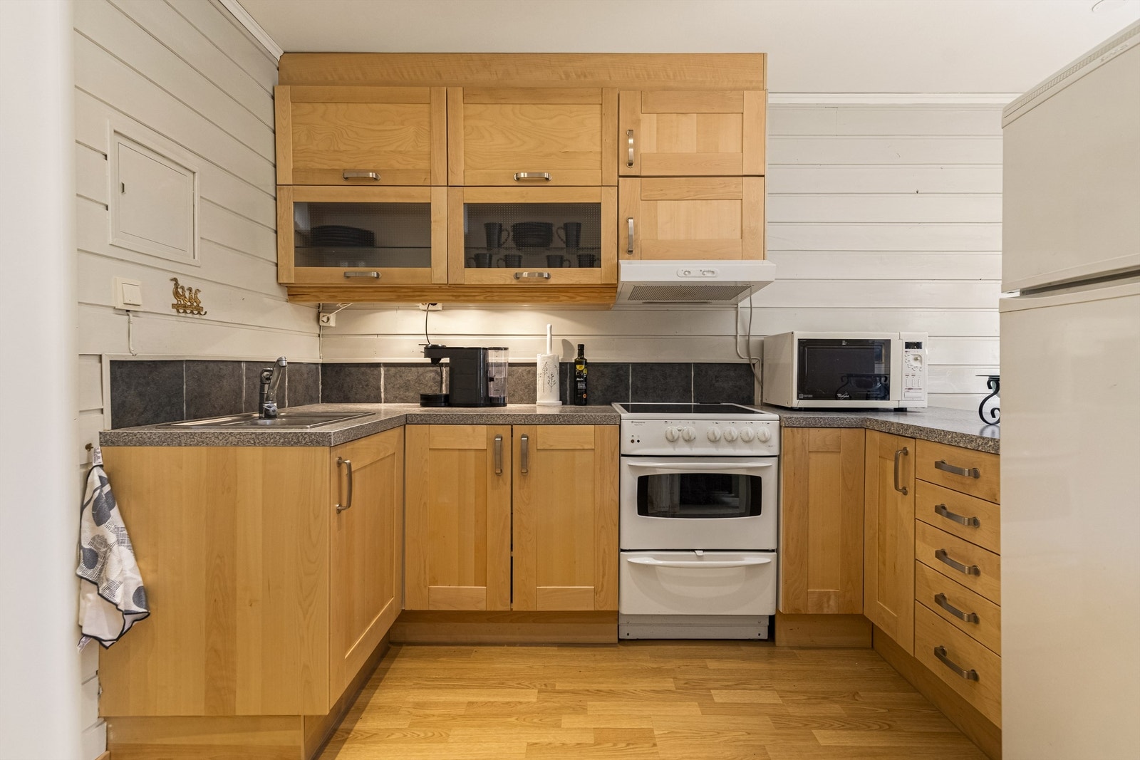 Kjøkkeninnredning fra Ikea med laminert benkeplate og fliser over benken. Det er laminatgulv med gulvvarme. Galleribilde