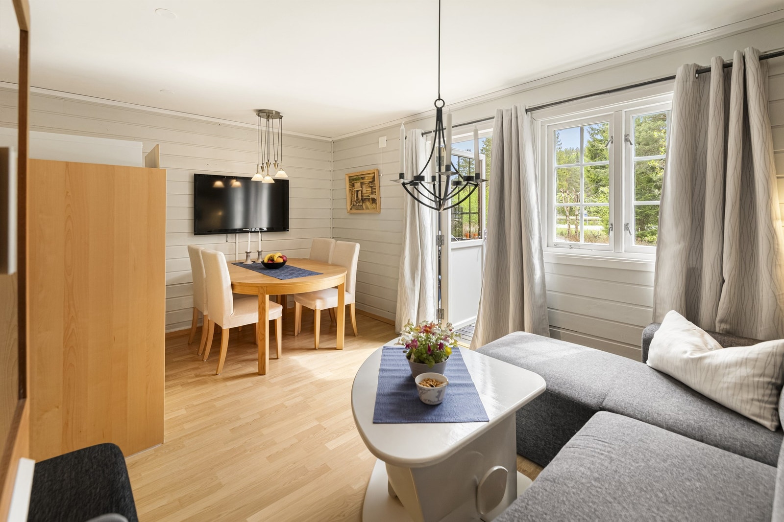 Stuen har plass til både sofagruppe og spisebord. Veggene er lysmalte Galleribilde