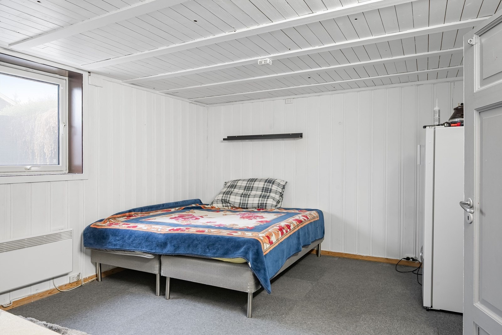 Rommet har lunt teppe på gulv, lysmalte overflater og to store vinduer. Det gjøres oppmerksom på at rommet ikke er godkjent for varig opphold. Galleribilde