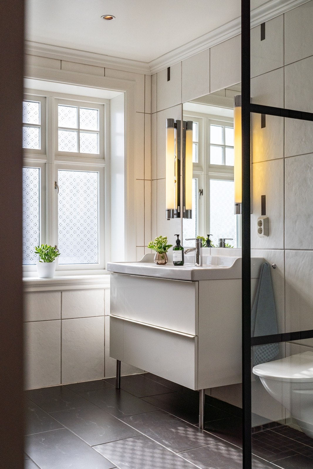 Badet inneholder servant i møblement, speil, vegghengt toalett, badekar og dusjhjørne. Galleribilde