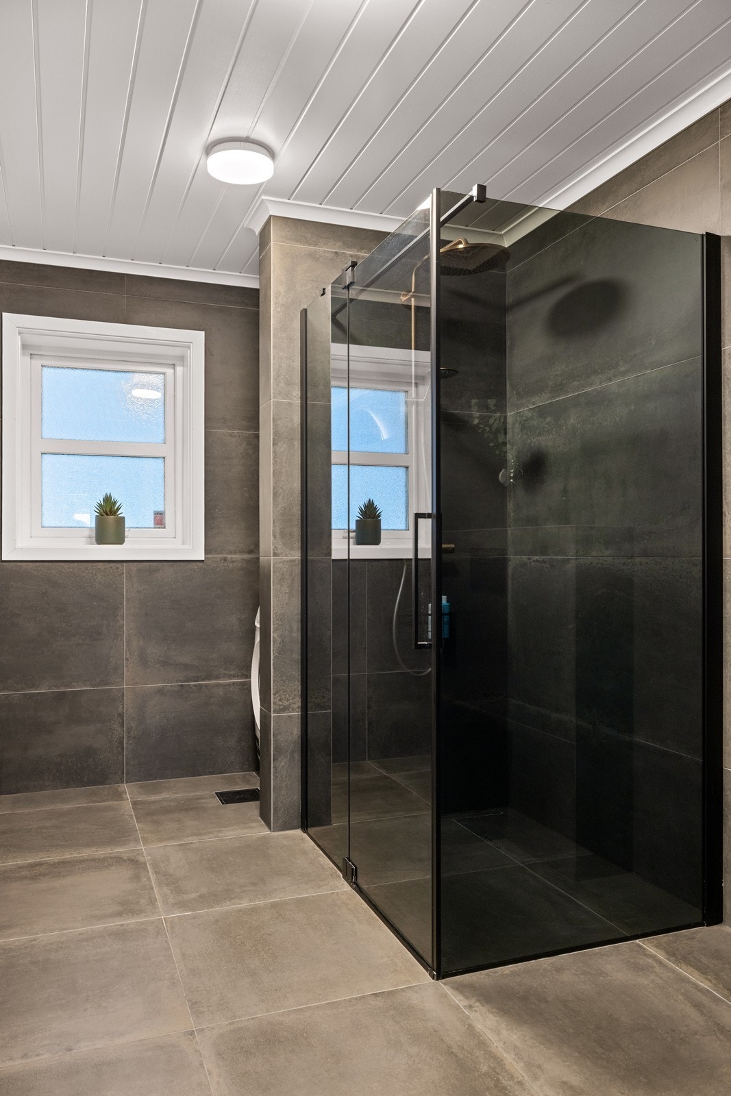 Dusjsonen har store fliser, slukrenne inntil veggen og elegante dusjvegger i glass. Galleribilde