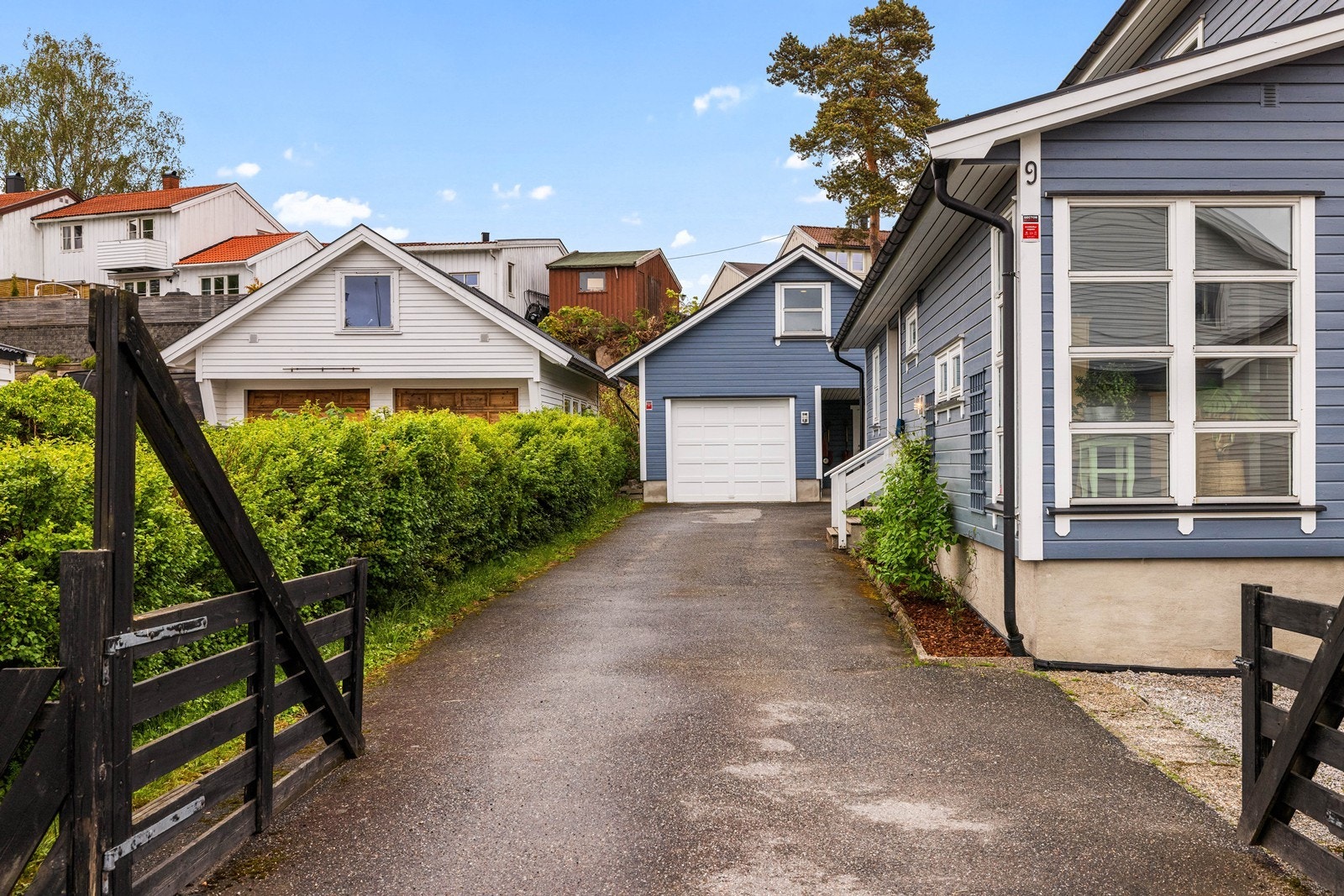 Gruset innkjørsel og gårdsplass med parkering i garasje og under carport. Galleribilde