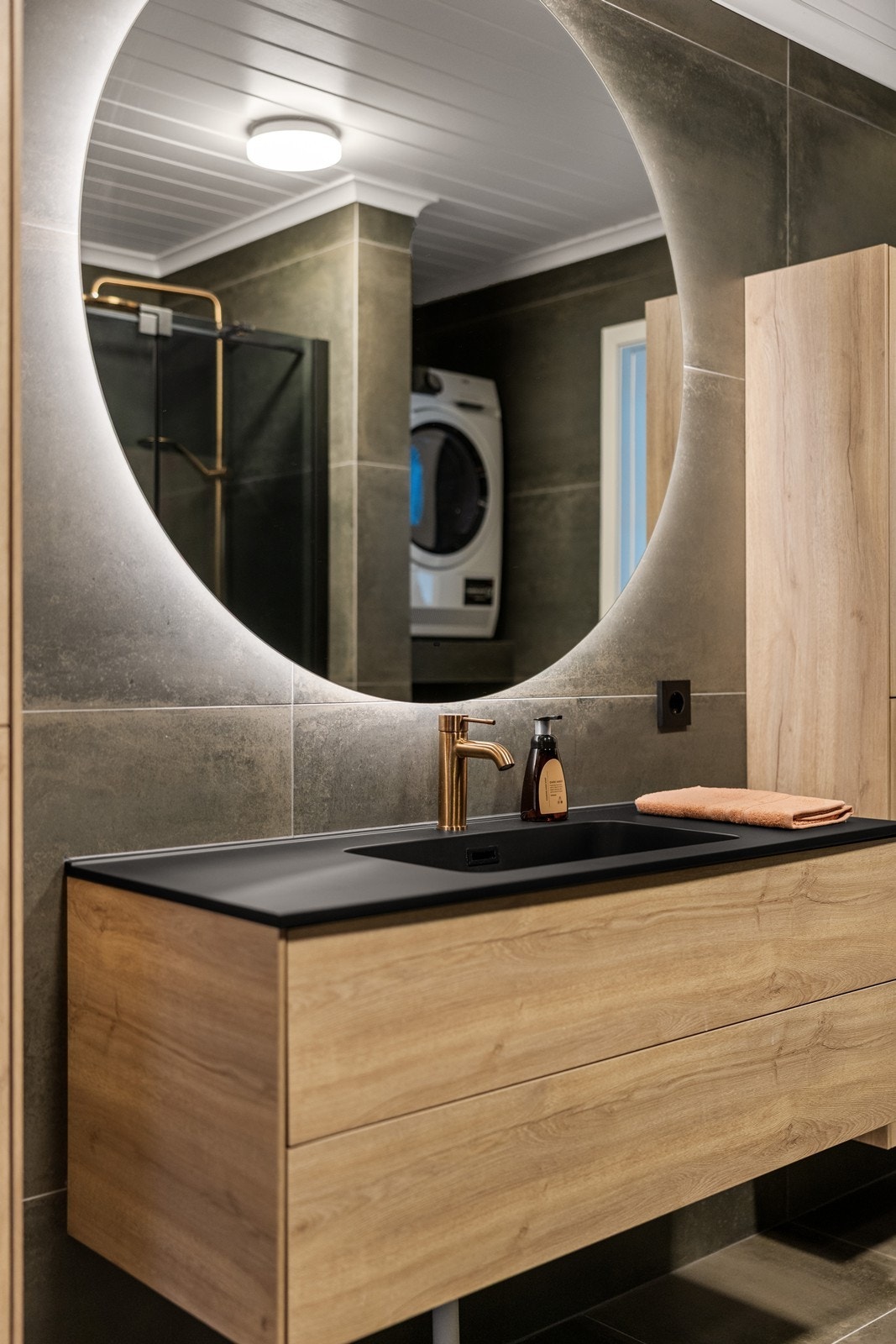 Badet har opplegg for vaskemaskin og et stort speil med integrert belysning. Galleribilde