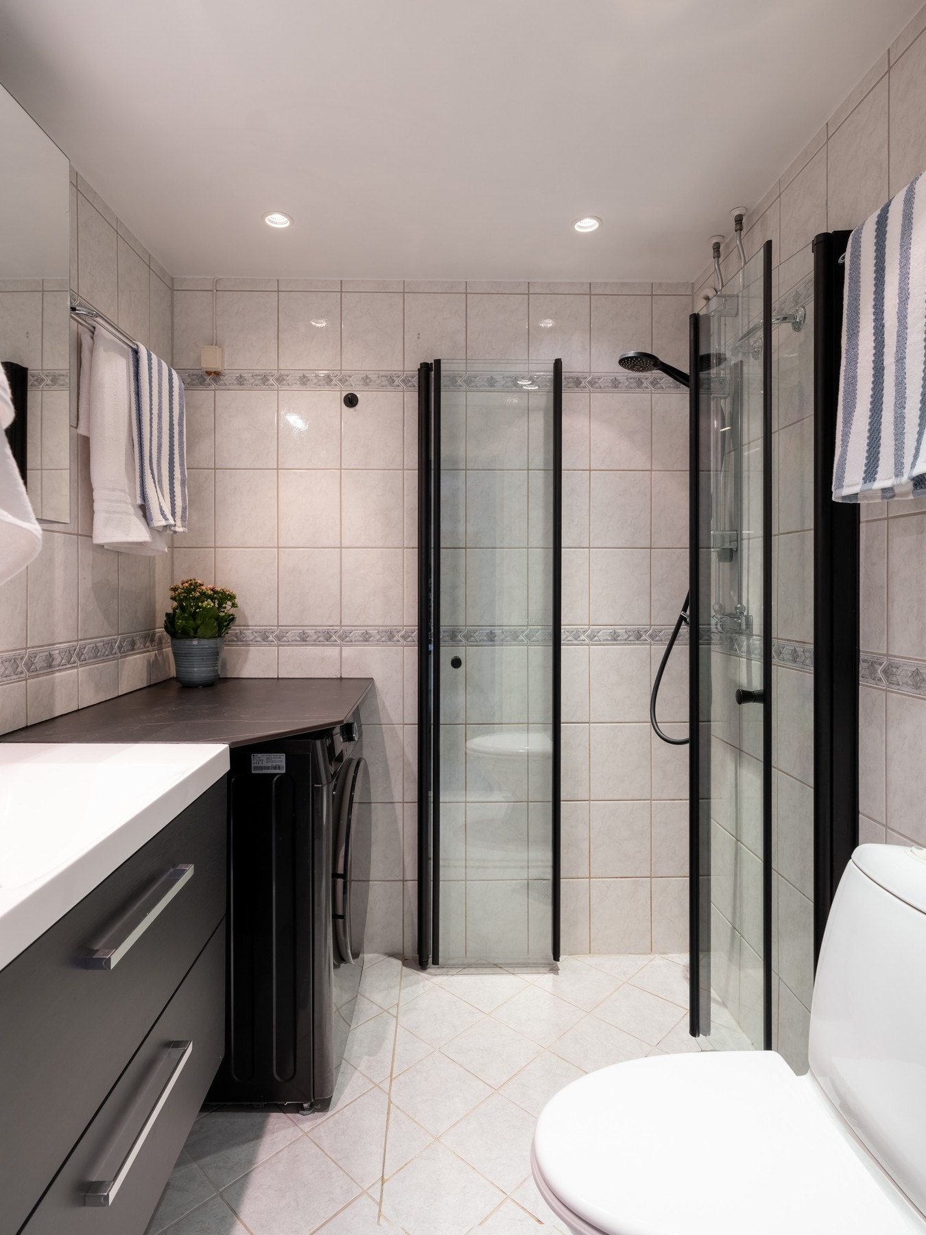 Boligens bad har lyse fliser, gulvvarme og downlights i himling. Badet ble pusset opp i regi av borettslaget i 2004. Galleribilde