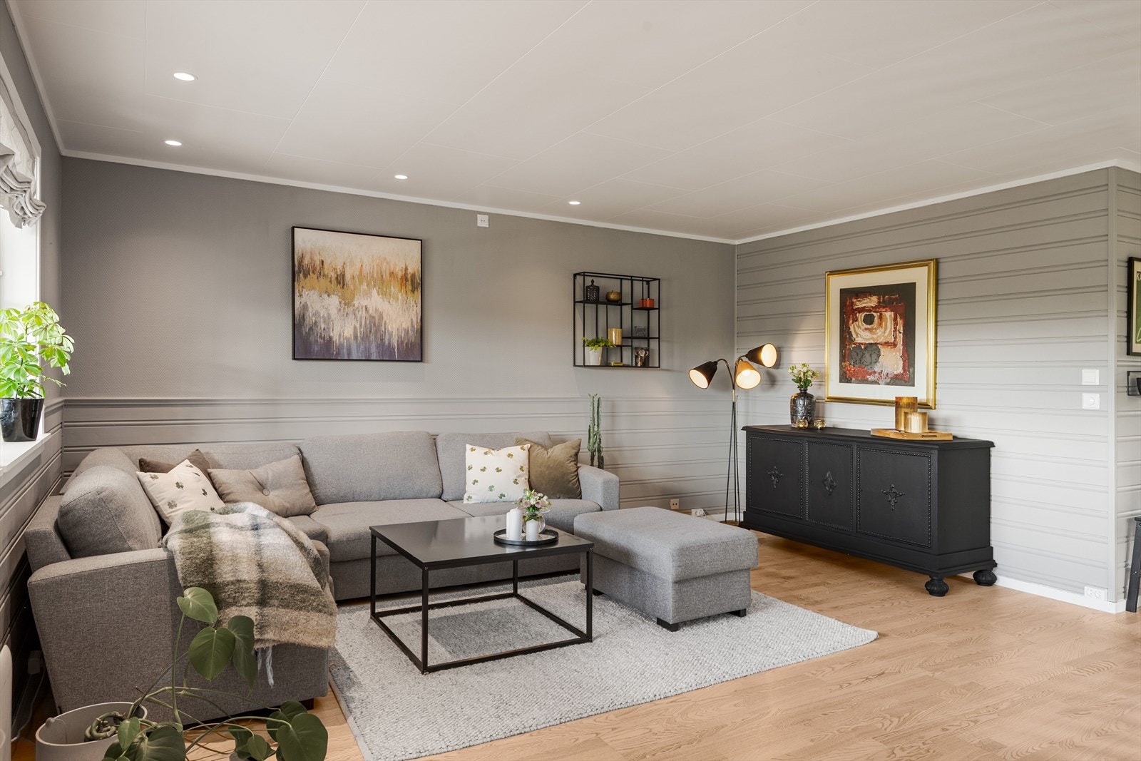 Stua er lys og innbydende med gråmalte vegger og lys himling med downlights. Galleribilde