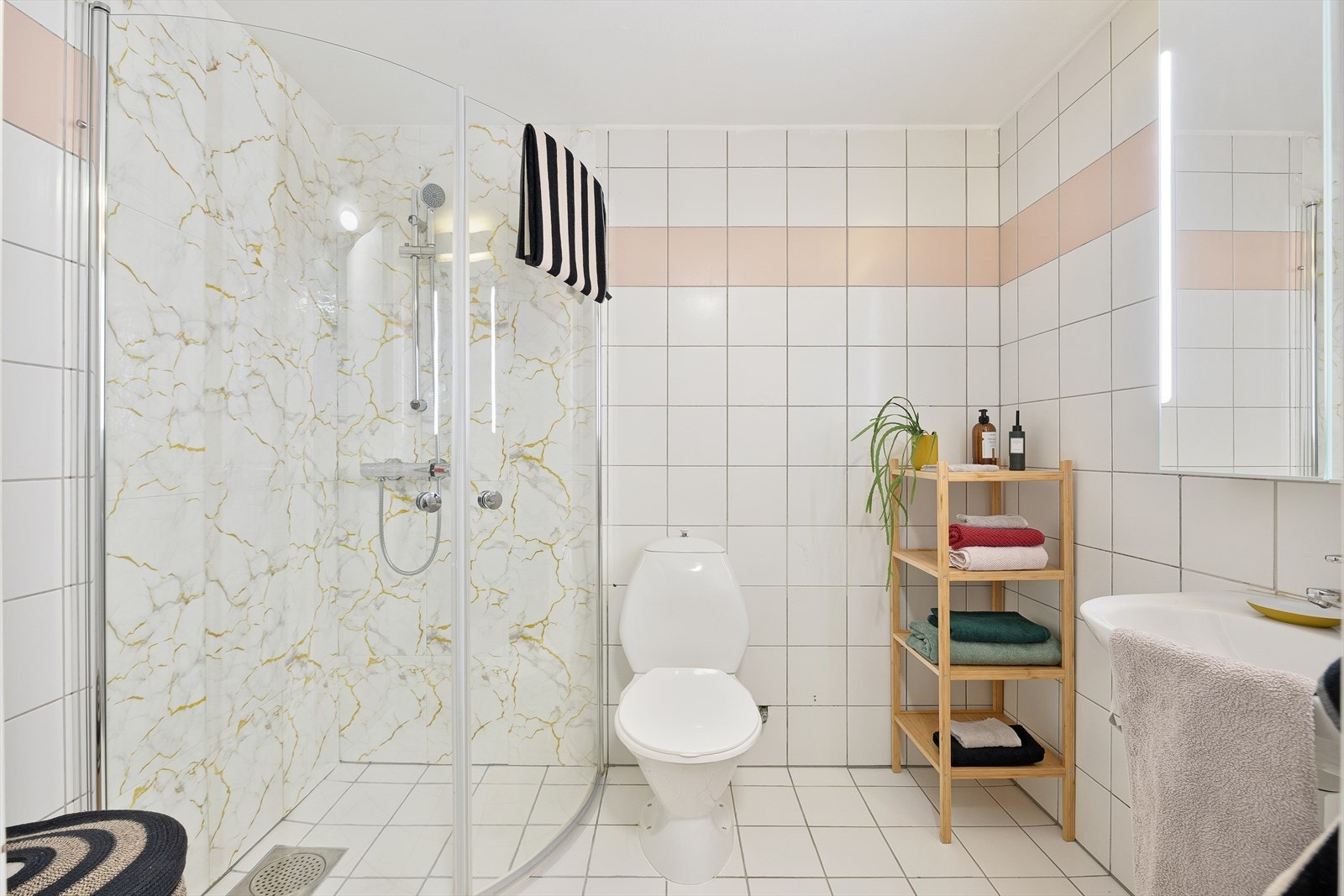 Badet er videre utstyrt med dusjhjørne, mekanisk avtrekk, gulvmontert toalett og servant i skap. Galleribilde