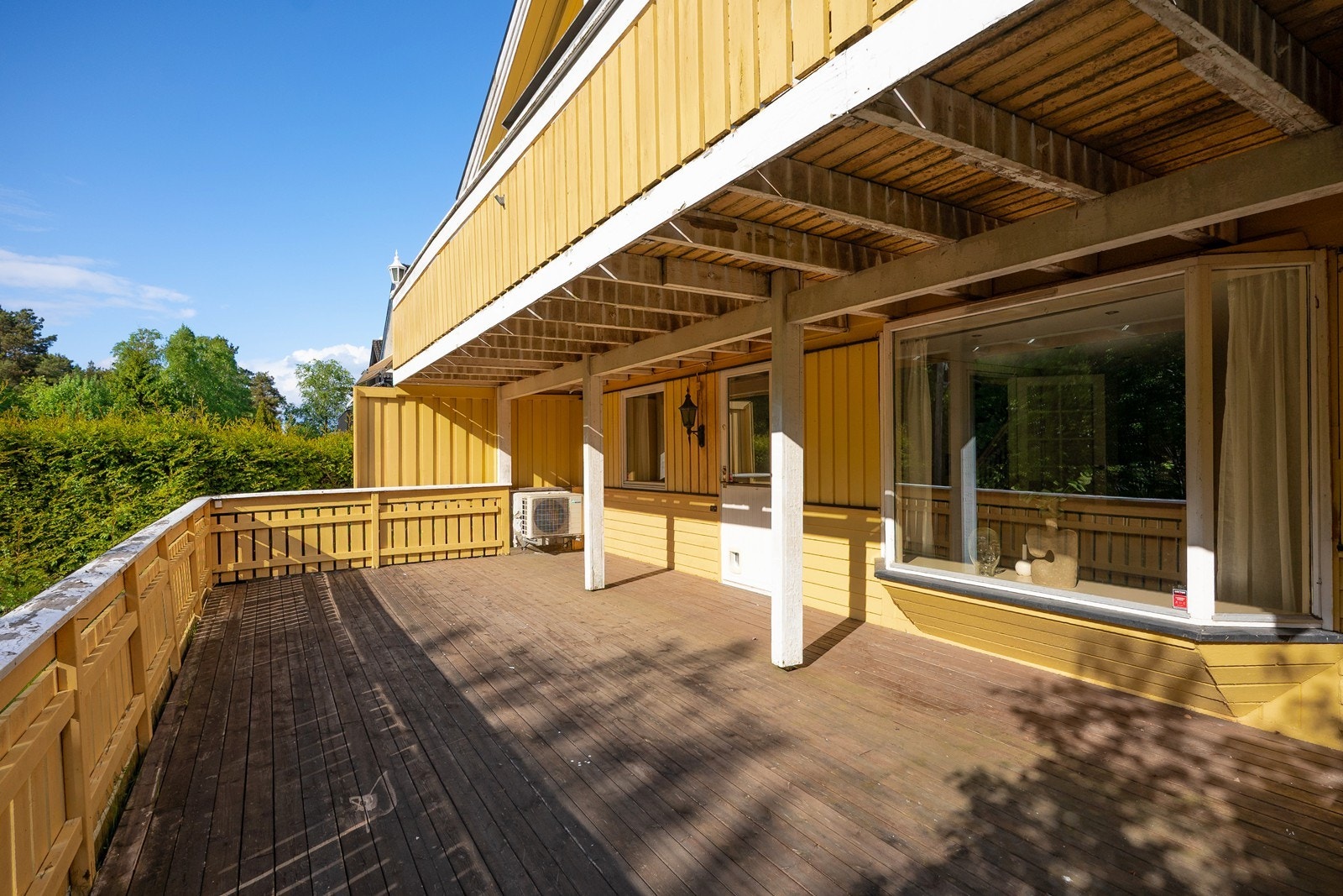 Fra gang i underetasjen fører verandadør ut til nedre del av boligens uteplass, med stor, vestvendt terrasse og hageflekk med gressplen og beplatning. Galleribilde