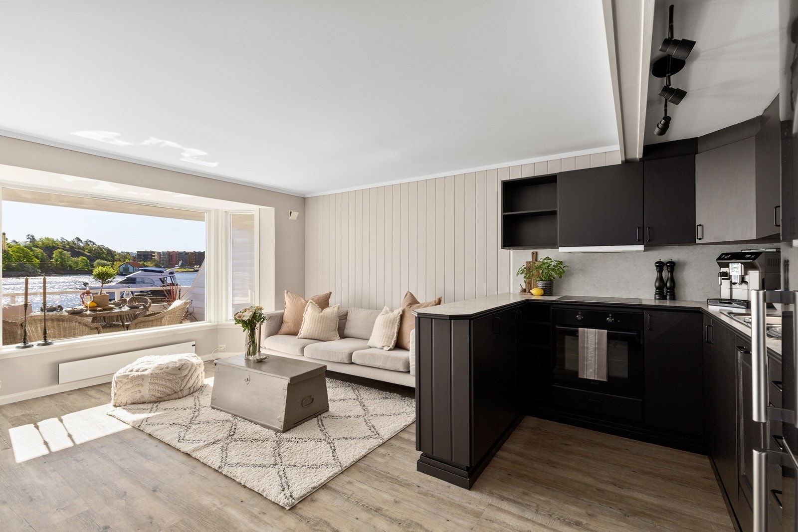 Lekkert kjøkken i åpen løsning mot stuen, som skaper en luftig og sosial romfølelse. Kjøkkenet har stilrene speilfronter og er malt i moderne fargetoner som gir et elegant uttrykk og naturlig sonedeling i rommet. Galleribilde