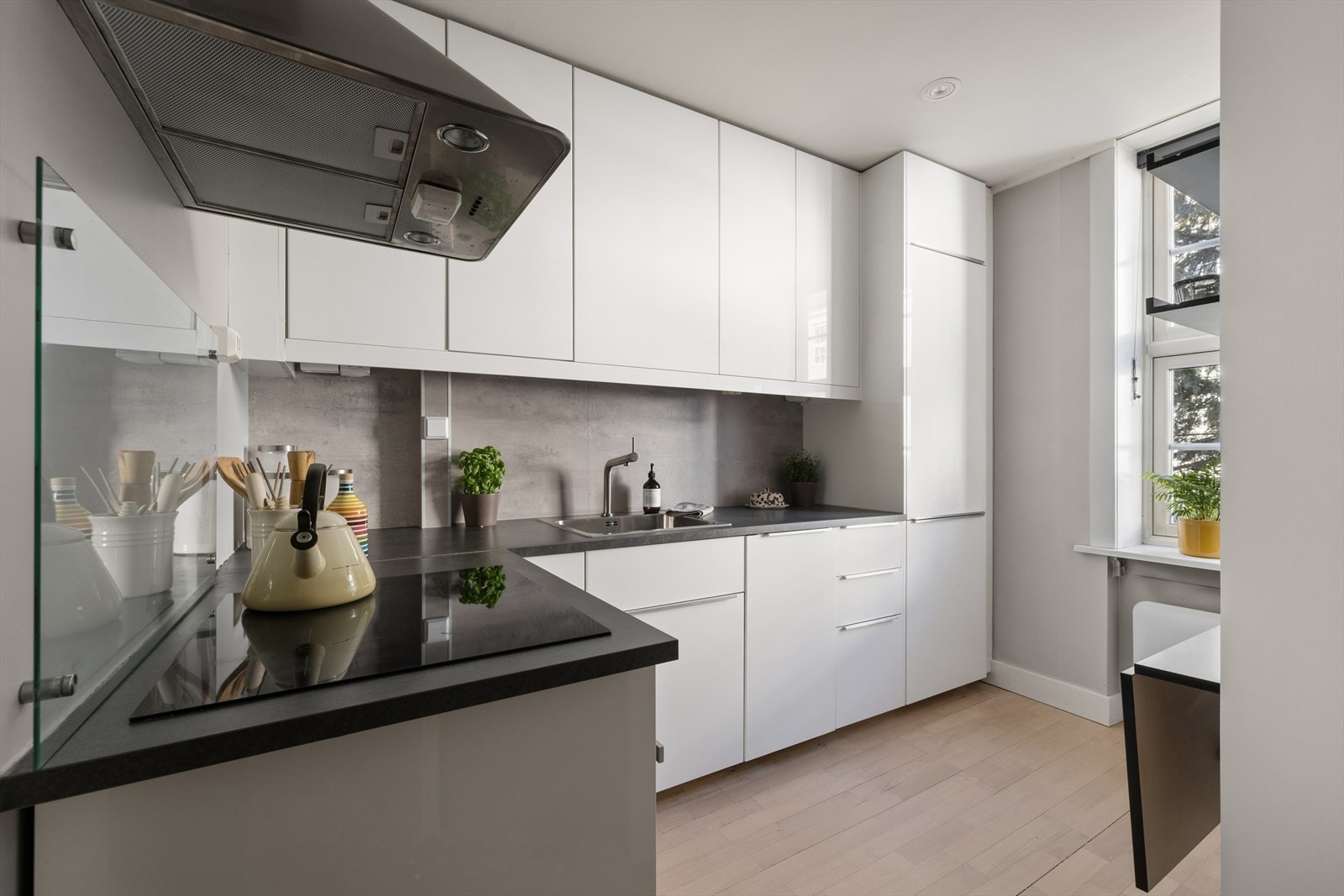 Moderne kjøkken med hvite fronter og mørk benkeplate. Praktisk planløsning med god arbeids og lagringsplass. Galleribilde