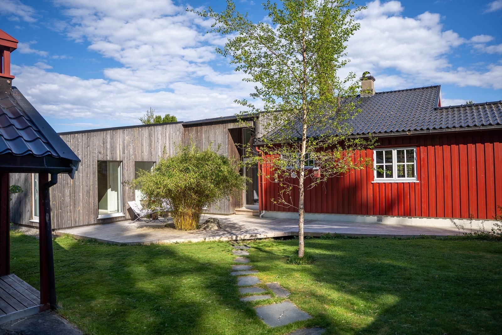Tilbyggets rolige fasade mot hagen, med brosteinsti, bambus og egen uteplass. Galleribilde
