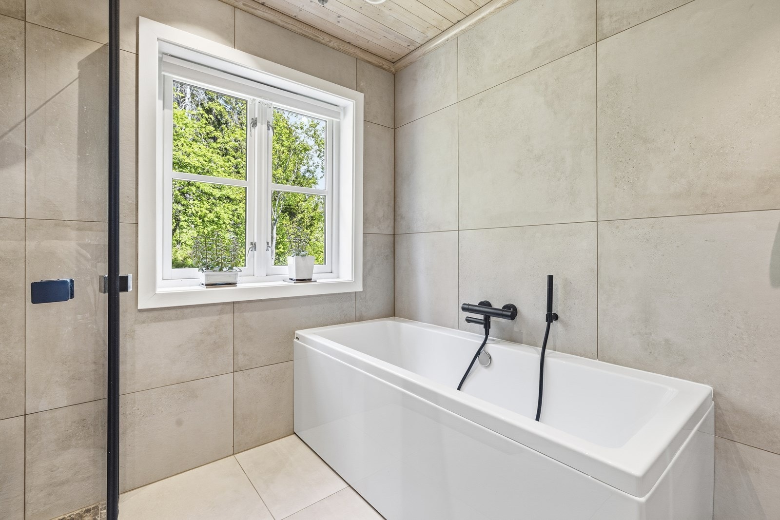 Badet er innredet med vegghengt toalett og badekar Galleribilde