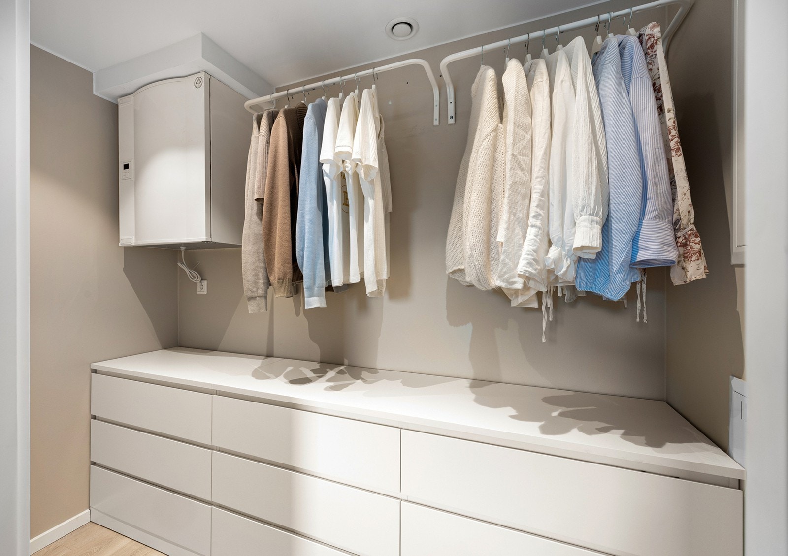 Praktisk walk-in closet med lyse overflater og downllights i himling. Galleribilde
