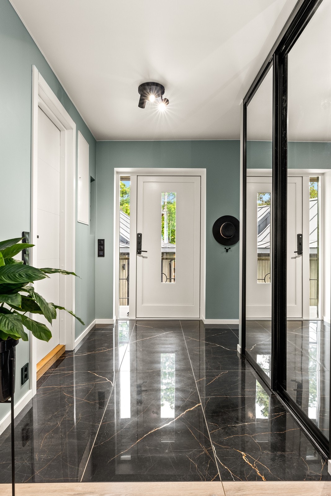 Hallen i første etasje har flislagt gulv og en malt tretrapp som fører opp til andre etasje. Galleribilde