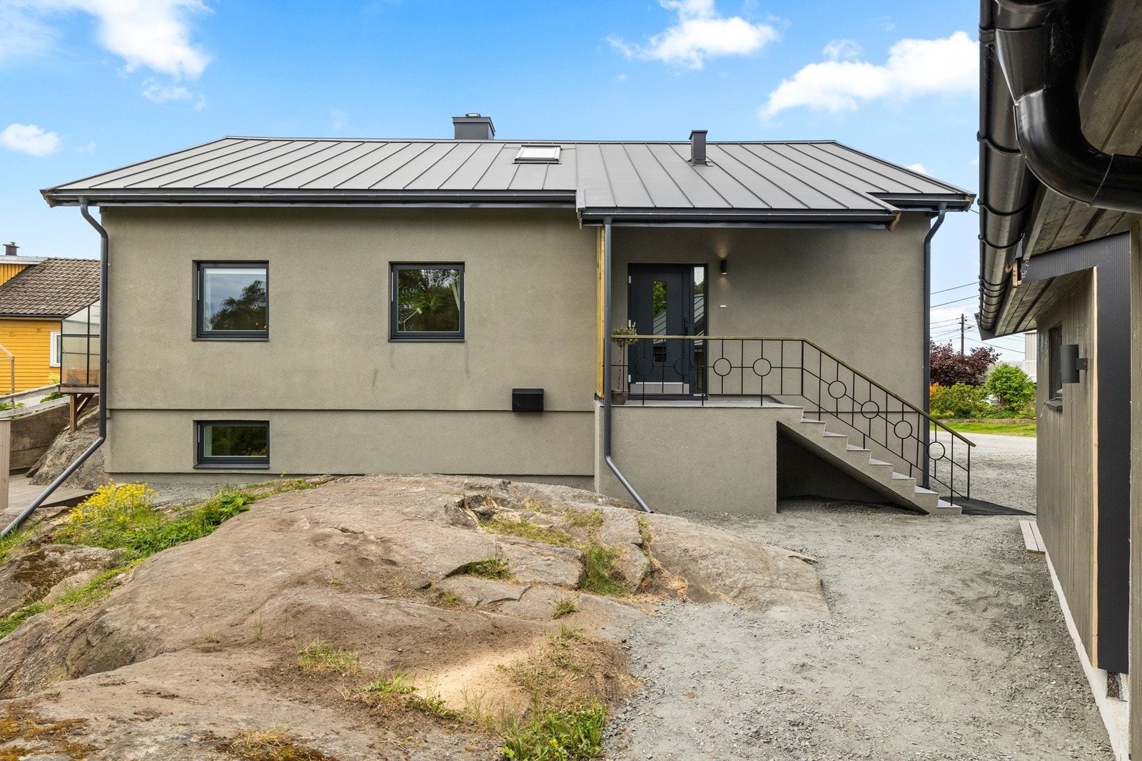Inngangsparti til hoveddelen ligger i bakkant av huset og på denne siden er det naturtomt. Eiendommen er bygget på fjellgrunn og har en gruslagt gårdsplass. Galleribilde
