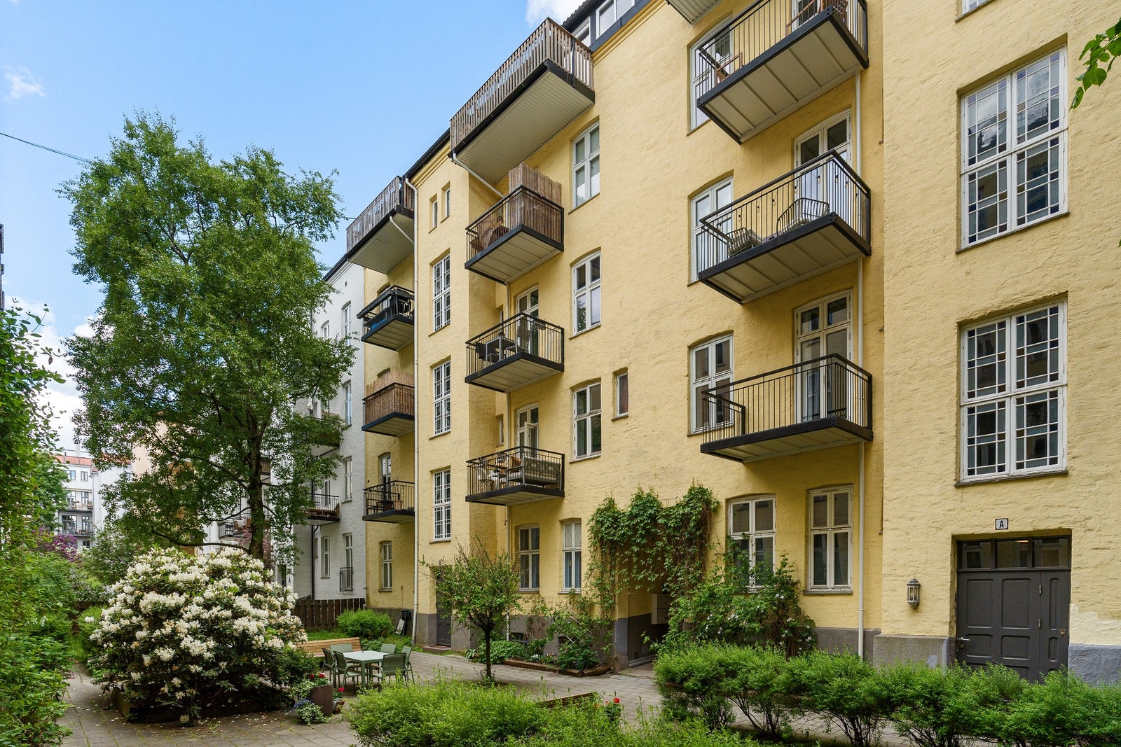 Bakgården er pent opparbeidet med sittegrupper, variert beplantning, grønne trær og blomster som skaper en frodig og hyggelig atmosfære gjennom vår- og sommermånedene. Bakgården er omkranset av vakre, klassiske bygårder. Galleribilde