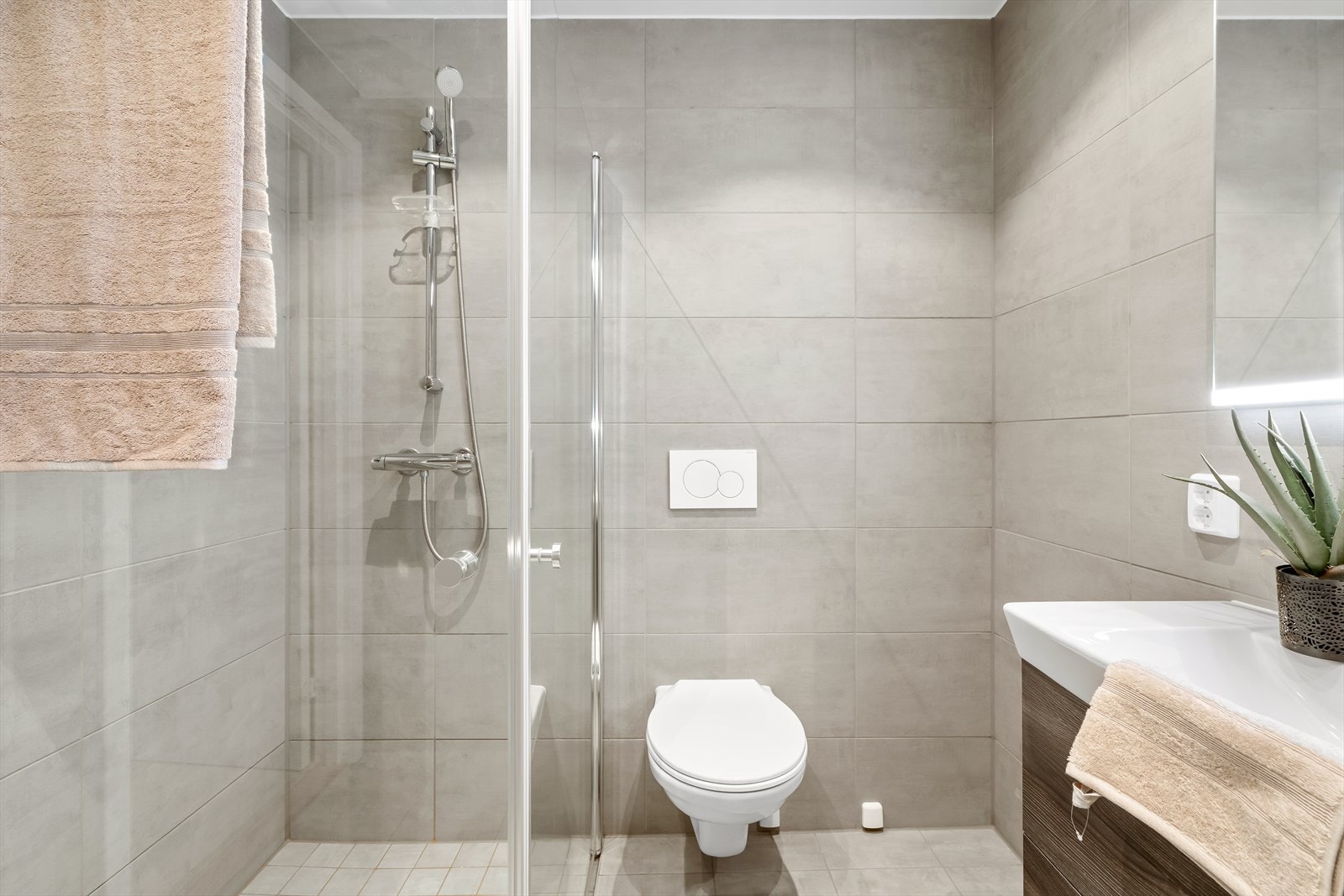 Store flisformat og lyse overflater gir badet et stilrent preg. Galleribilde