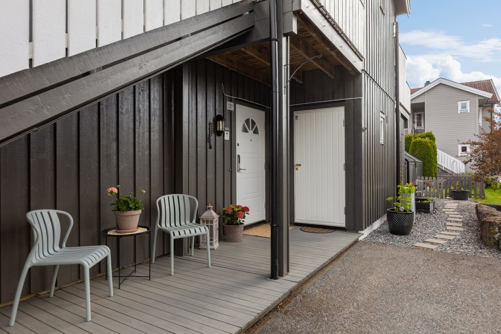 Hyggelig overbygd inngangspartit med platting, og ytterdøren er hvitmalt med glassfelt og kodelås. Legg merke til den nydelige "stien" til uteområdet. Galleribilde
