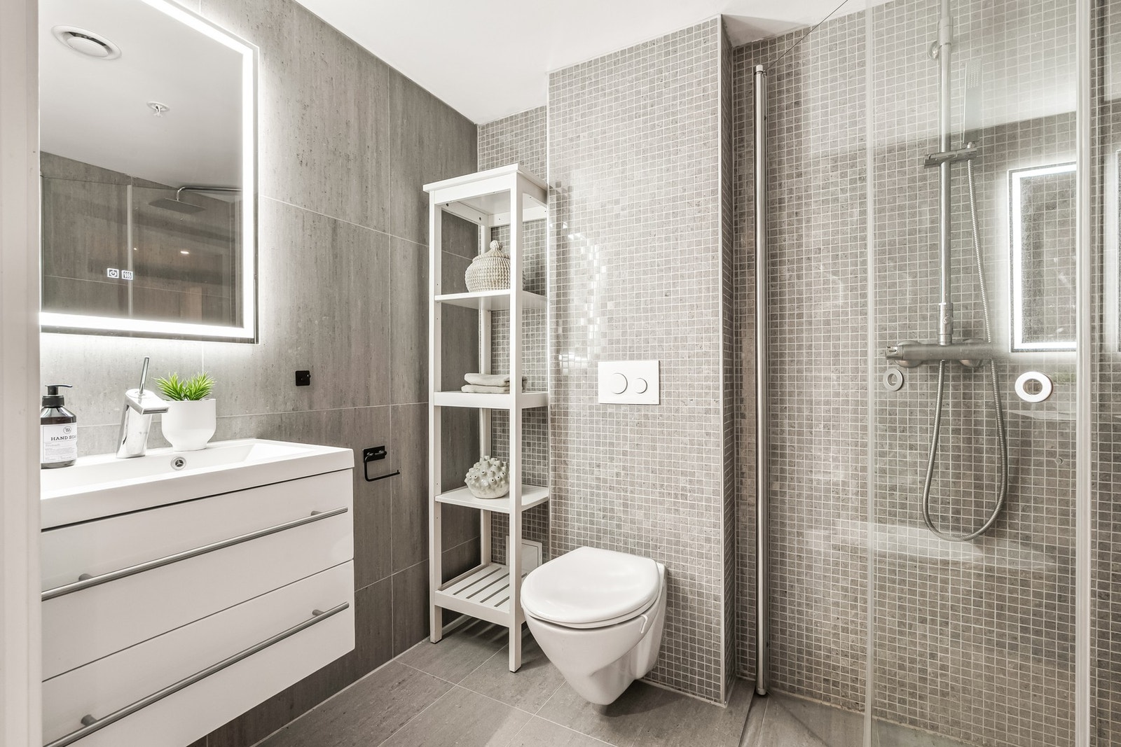 Baderom 2. Innbydende bad, med pene flisvalg og varme i gulv. Servantskap med to skuffer gir lagringsplass for toalettartikler, mm. Det er videre montert speil med lys over servant. Badet er utstyrt med veggmontert klosett, samt eget dusjhjørne med svingb Galleribilde