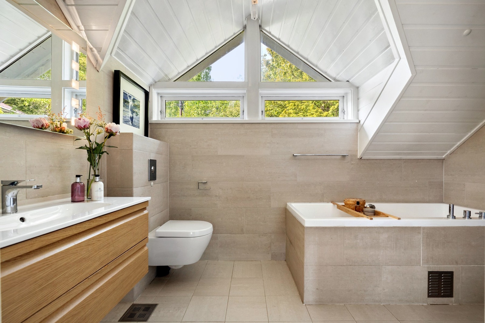 Badet i 2. etasje er flislagt med flotte beige fliser på både vegger og gulv, noe som gir rommet et stilrent uttrykk Galleribilde