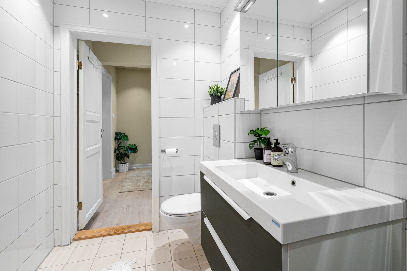 Badet er utstyrt med vegghengt toalett, servant med innredning og dusjsone Galleribilde