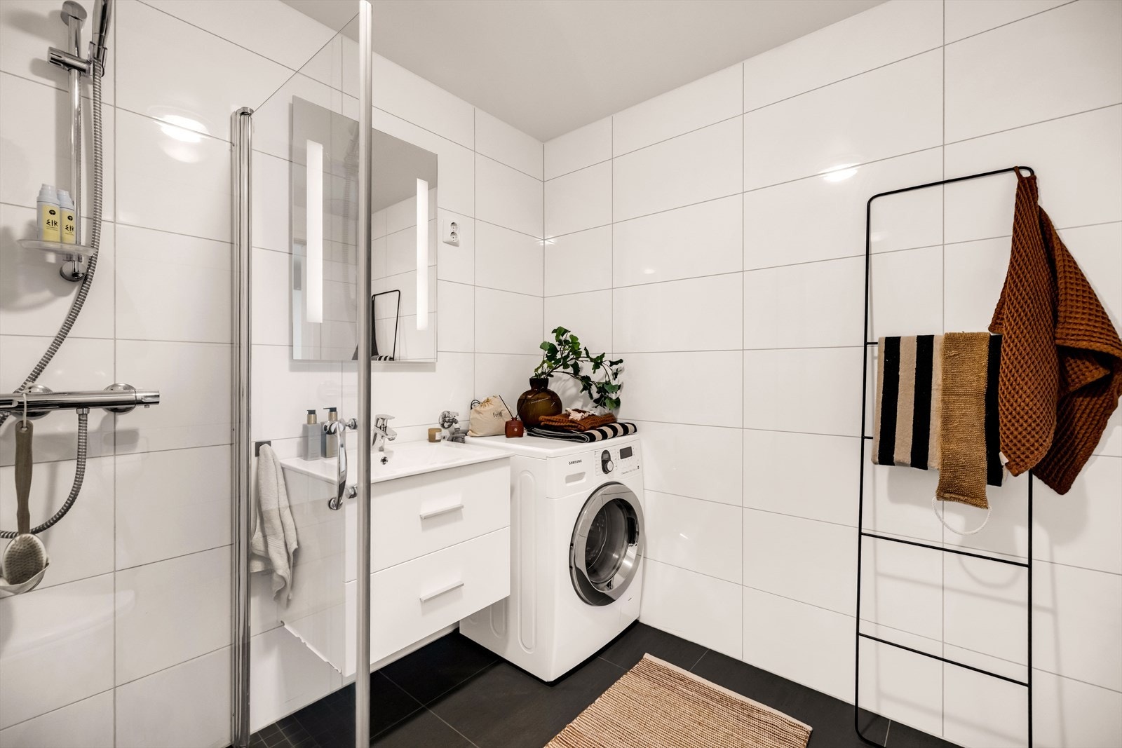 Badet er innredet med vegghengt klosett, servant nedfelt i innredning, speil med lys og dusjhjørne svingbare glassdører. Galleribilde