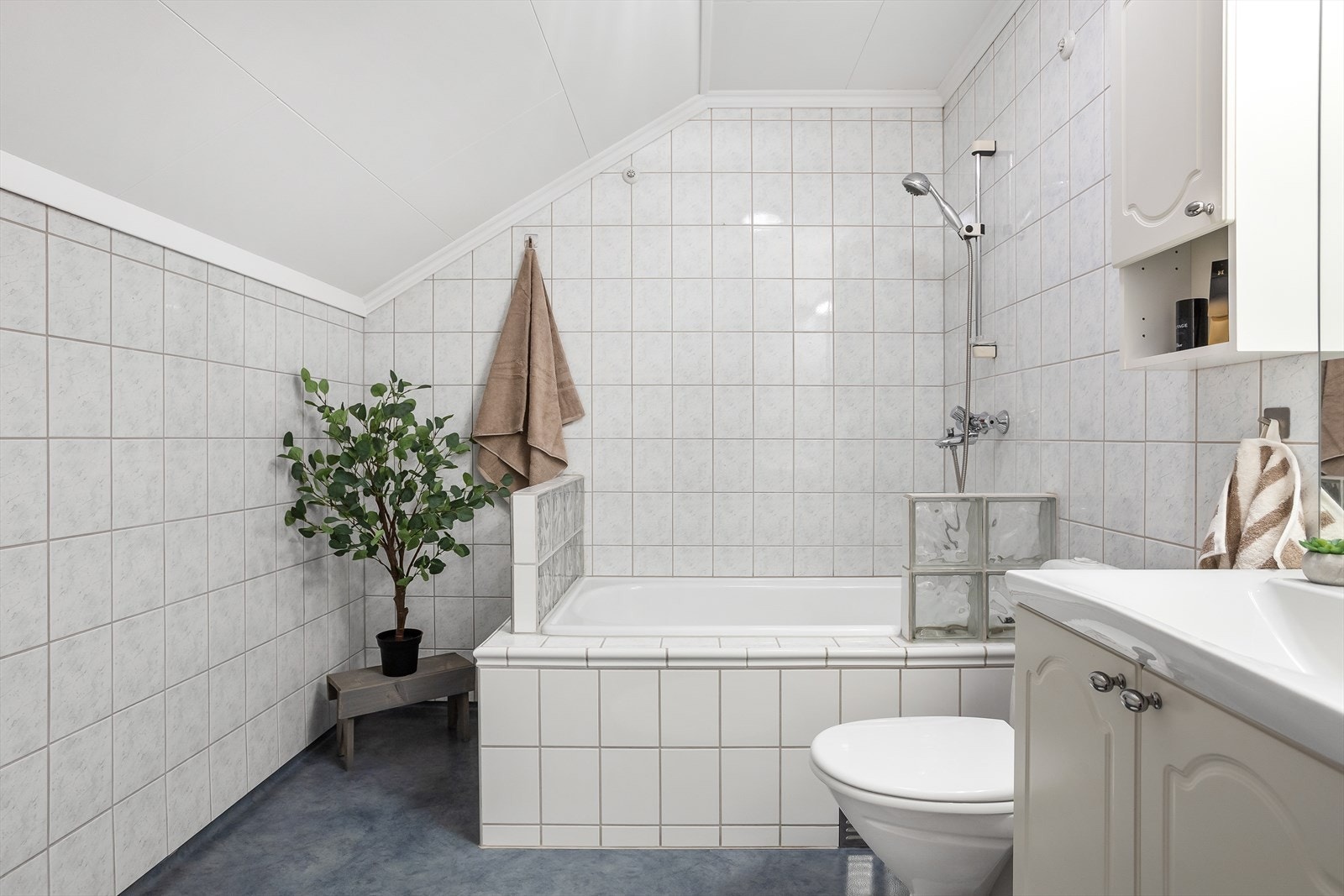 Badet på loftet har fliser på veggene, våtromsbelegg på gulvet og et deilig badekar. Galleribilde