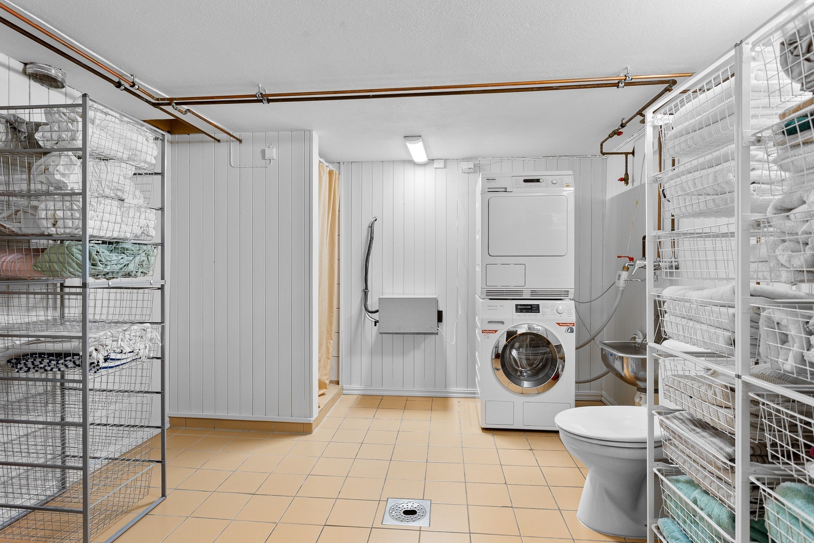 Vaskerom med flislagt gulv med varme i kjelleretasjen. Innredet med vegghengt utslagsvask. Dusjhjørne med forheng og gulvstående toalett. Opplegg for vaskemaskin. Galleribilde