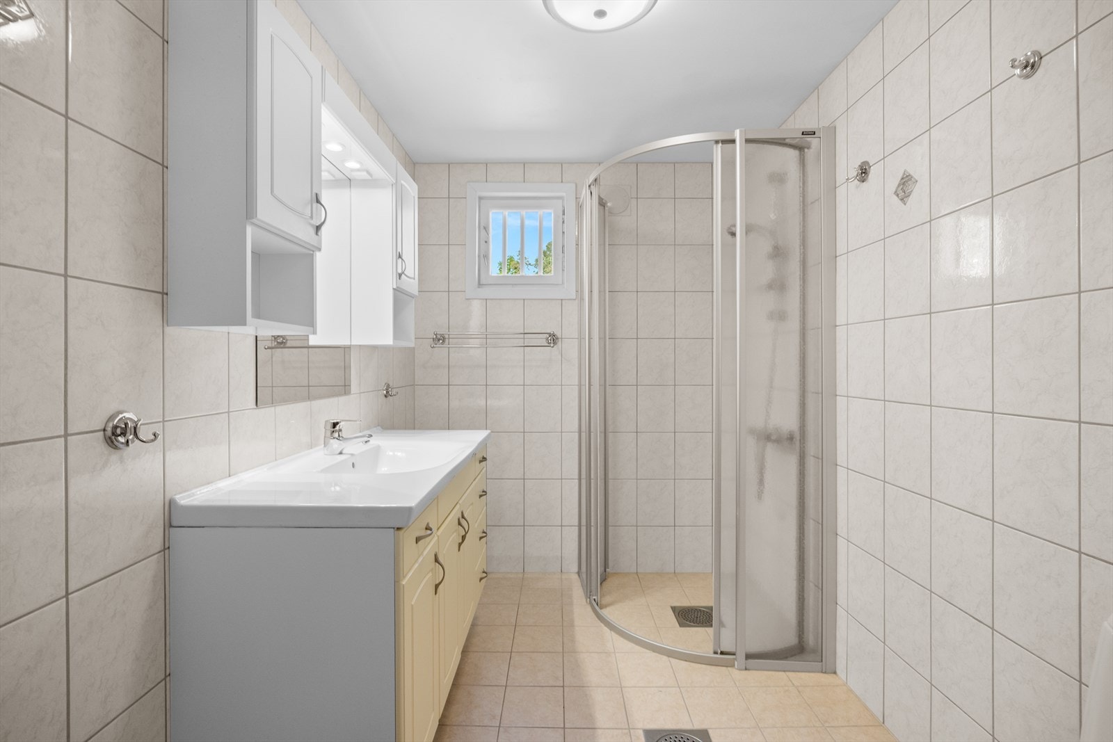 Helfliset bad i 1. etasje med varmekabler i gulv og lite vindu. Innredet med toalett og dusjhjørne, stor baderomsinnredning med veggskap. Badet ble pusset opp i 2003 Galleribilde