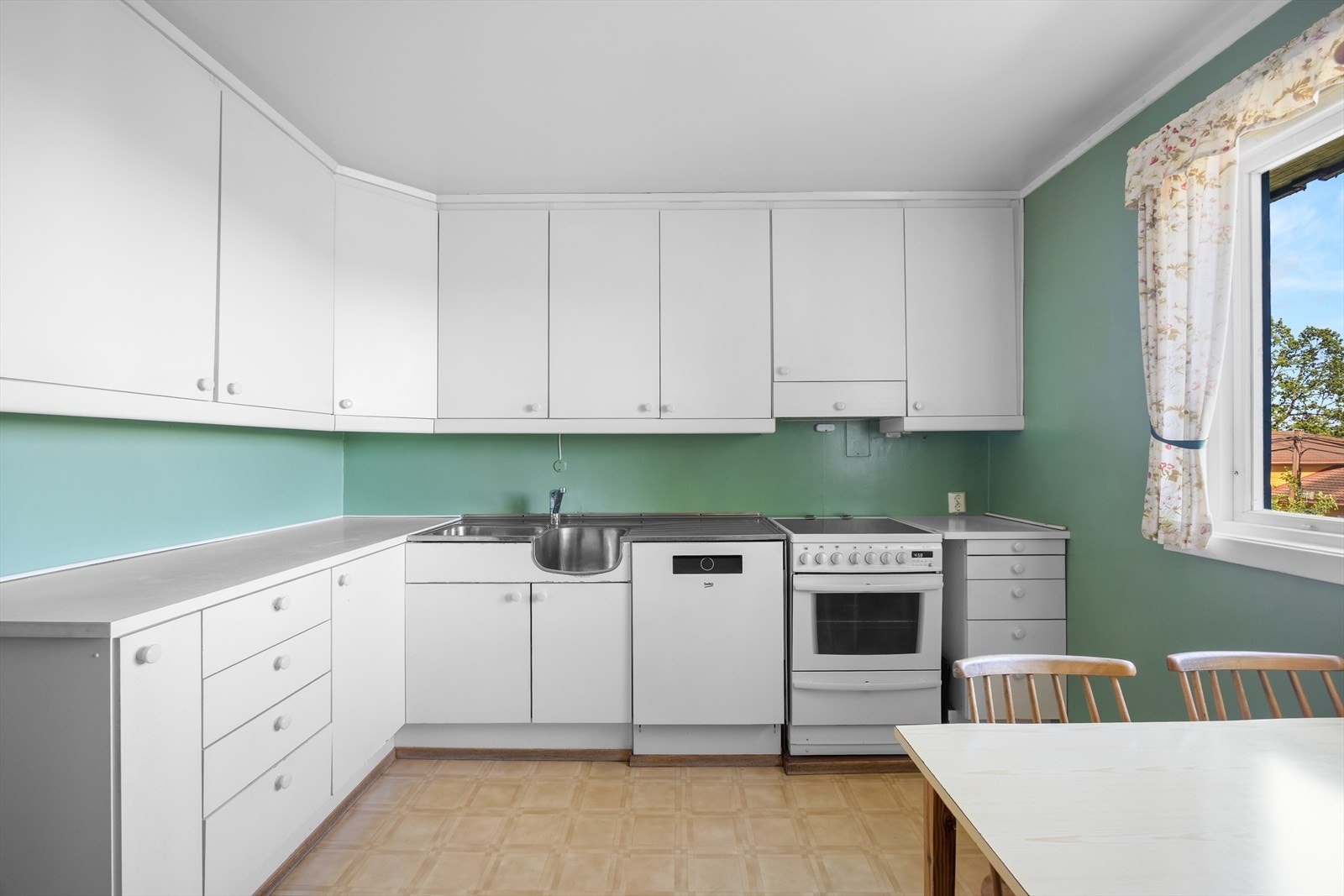 Kjøkken i 1. etasje med gode oppbevaringsmuligheter. Kjøkkeninnredningen har glatte fronter i hvit utførelse og laminat benkeplate med nedfelt vaskekum Galleribilde
