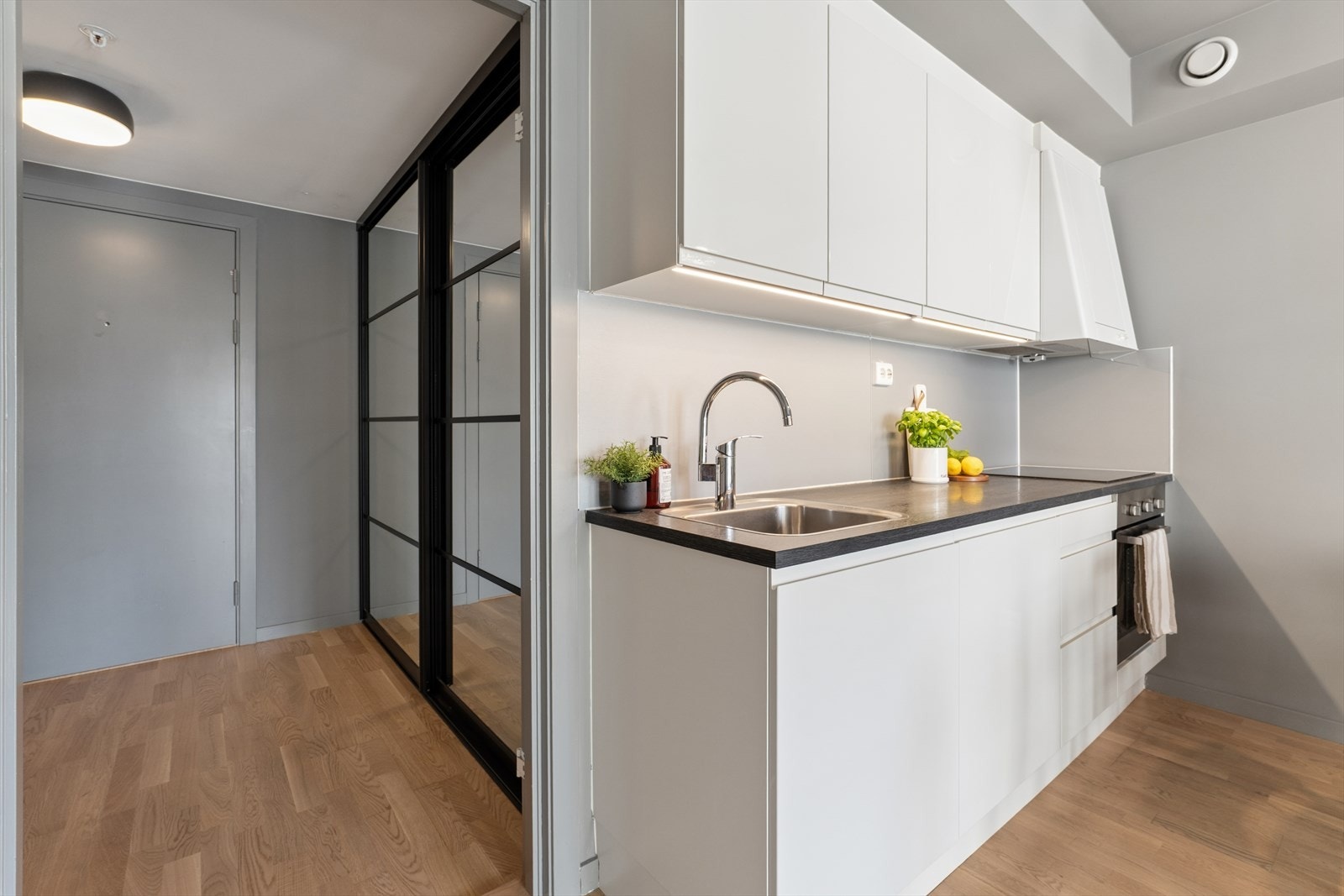 Kjøkkeninnredningen er pent utført med hvite, glatte profiler og laminat benkeplate med nedfelt stål benkebeslag. Galleribilde