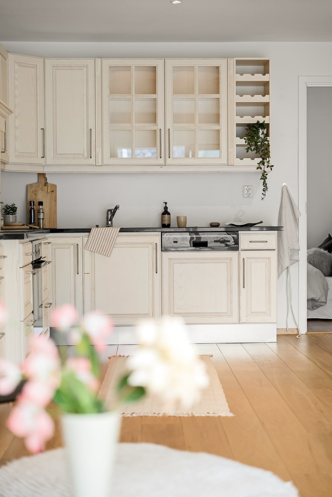 Klassisk kjøkkeninnredning med rikelig med skap- og skuffeplass, profilerte, lyse fronter med demping i skuffer og skap. Det er montert stålvask med to kummer nedfelt i benkeplate av stein. Galleribilde